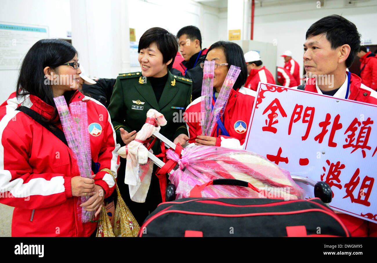 Quanzhou. 8 Mar 2014. Una ispezione di frontiera officer di Quanzhou porto presenta fiori per le donne da Jinmen del sud della Cina di Taiwan per la Giornata internazionale della donna in Quanzhou, una città costiera del sud-est della Cina di provincia del Fujian, Marzo 8, 2014, che è la Giornata internazionale della donna. Oltre 800 pellegrini da Jinmen arrivati in Quanzhou sabato per un viaggio di 3 giorni del pellegrinaggio. © Wei Peiquan/Xinhua/Alamy Live News Foto Stock