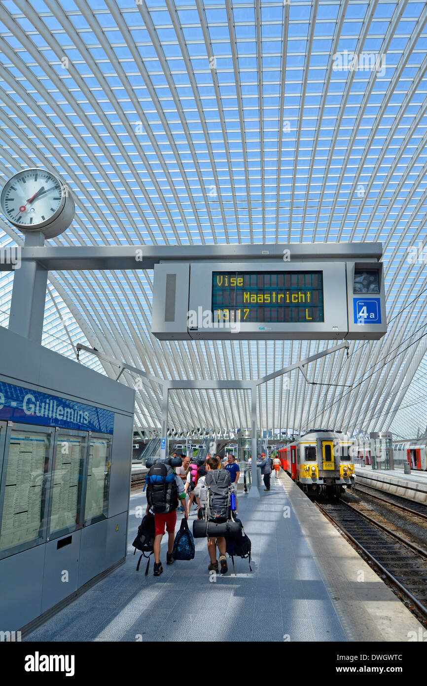 Gruppo Backpacker stazione ferroviaria piattaforma caricata con kit zaino in moderno trasporto pubblico tetto di vetro edificio scheda partenze & clock Belgio Liege Foto Stock
