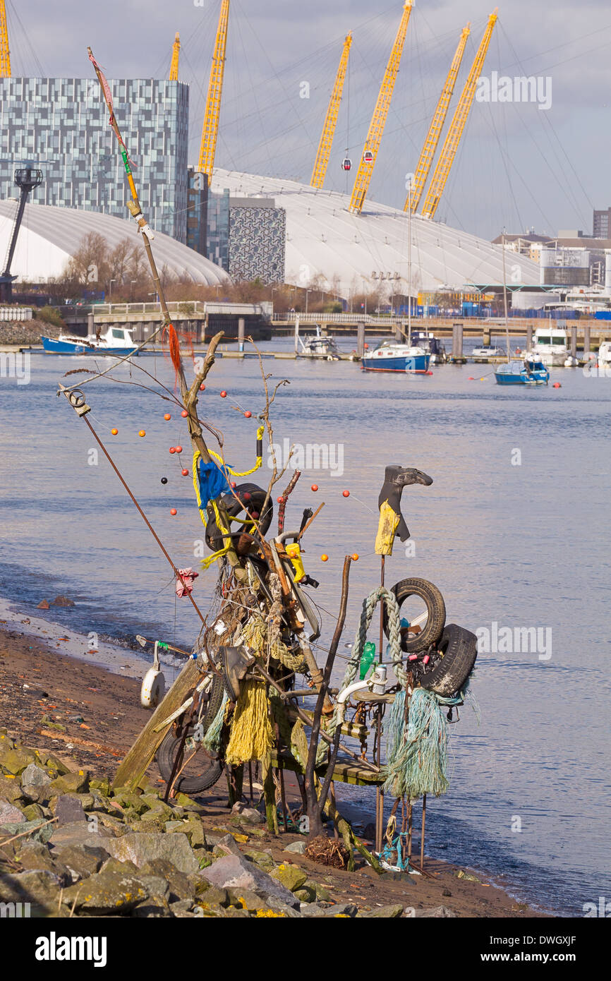 Un 'arte' installazione di articoli scartati sul Tamigi foreshore, con North Greenwich Peninsula in background Foto Stock