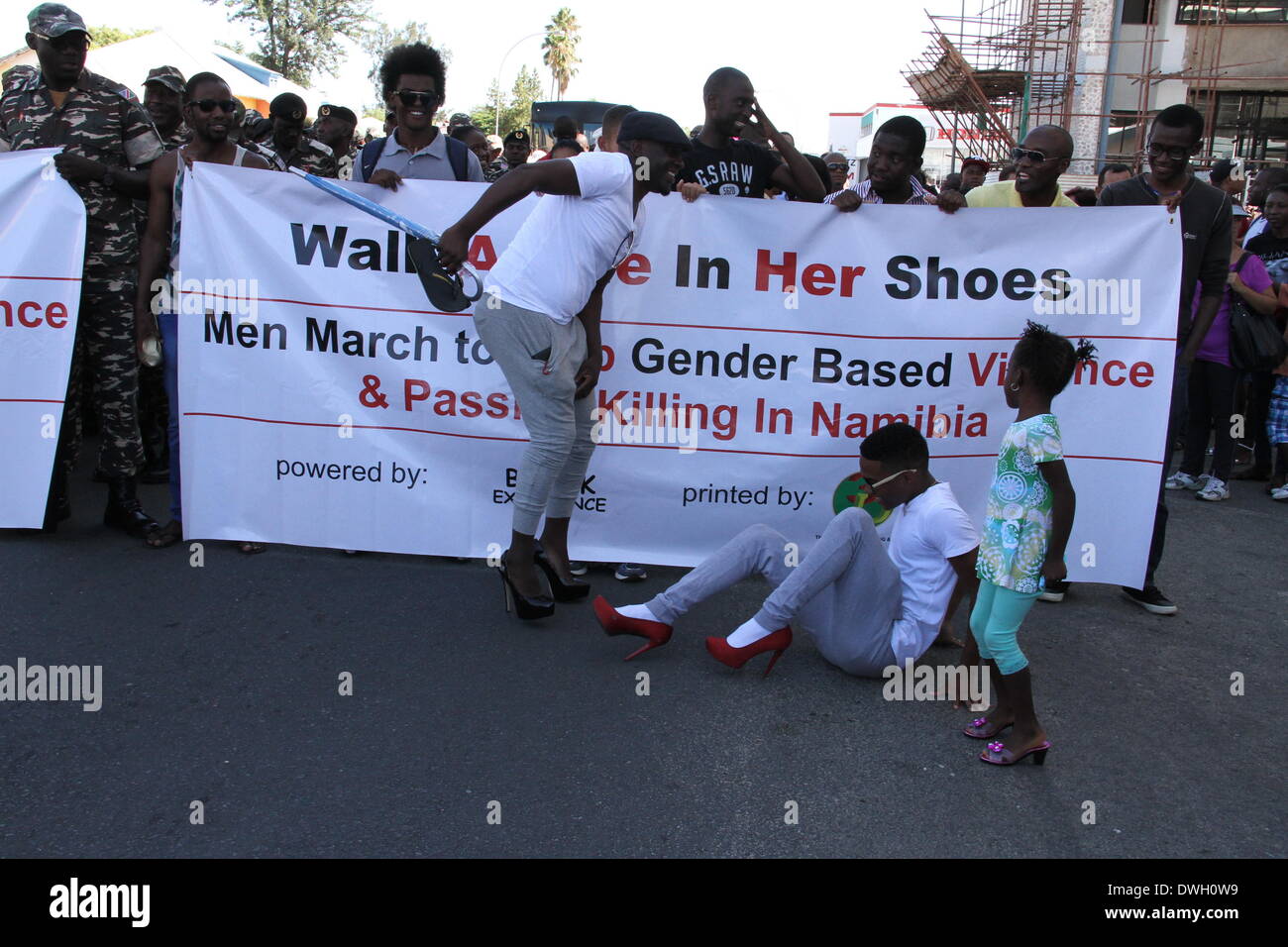 A Windhoek, Namibia. 8 marzo 2014. Un uomo che indossa tacchi alti cade a terra durante una marcia di protesta di genere violenza in Windhoek. Decine di uomini che indossano tacchi alti hanno partecipato al 'Men marzo per arrestare il genere basato violenza & Passione uccisione in Namibia' nella capitale della Namibia Windhoek il sabato. Il mese di marzo ha lo scopo di protestare contro la sovratensione di fatale crimini e la violenza contro le donne della Namibia sin dall'inizio di quest'anno, durante il quale periodo oltre dieci donne sono state uccise dai loro partner maschi nel sud-ovest del paese africano con una popolazione di credito: Xinhua/Alamy Live News Foto Stock