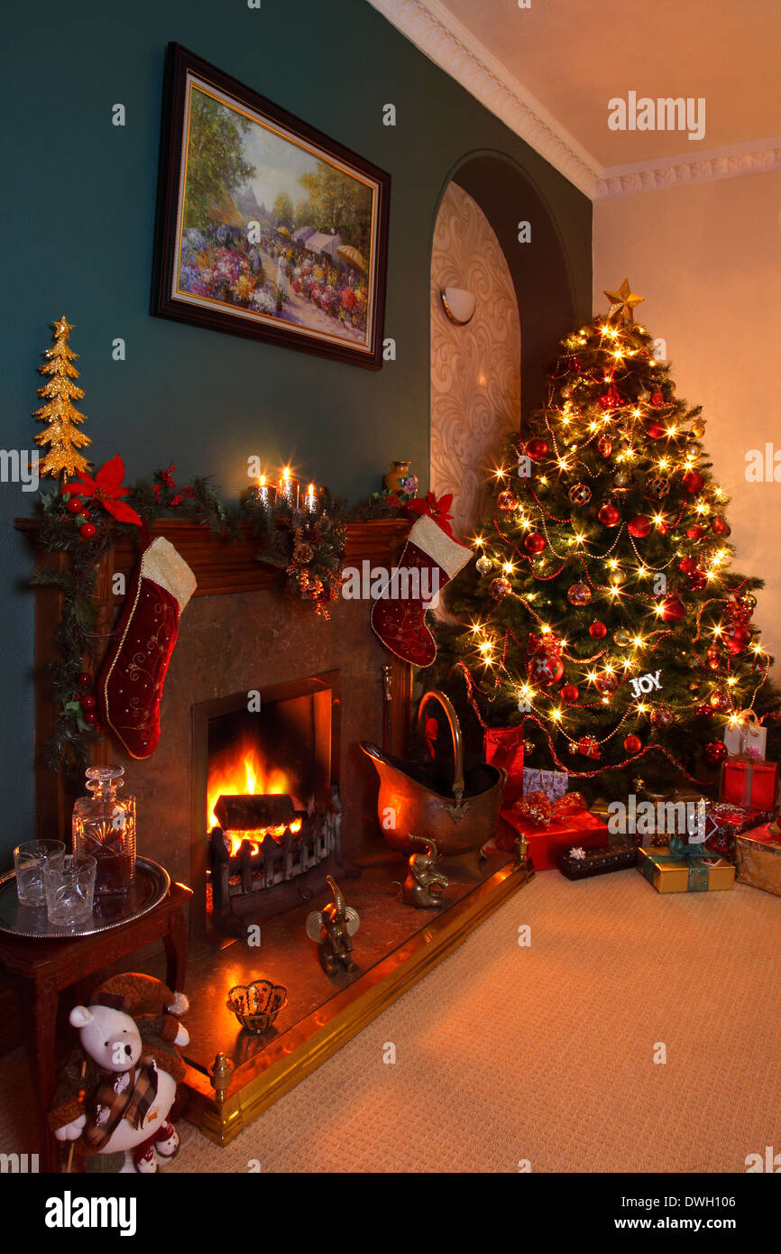 Celebrare il Natale a casa con un albero di Natale, regali e un bello e caldo il fuoco. Foto Stock