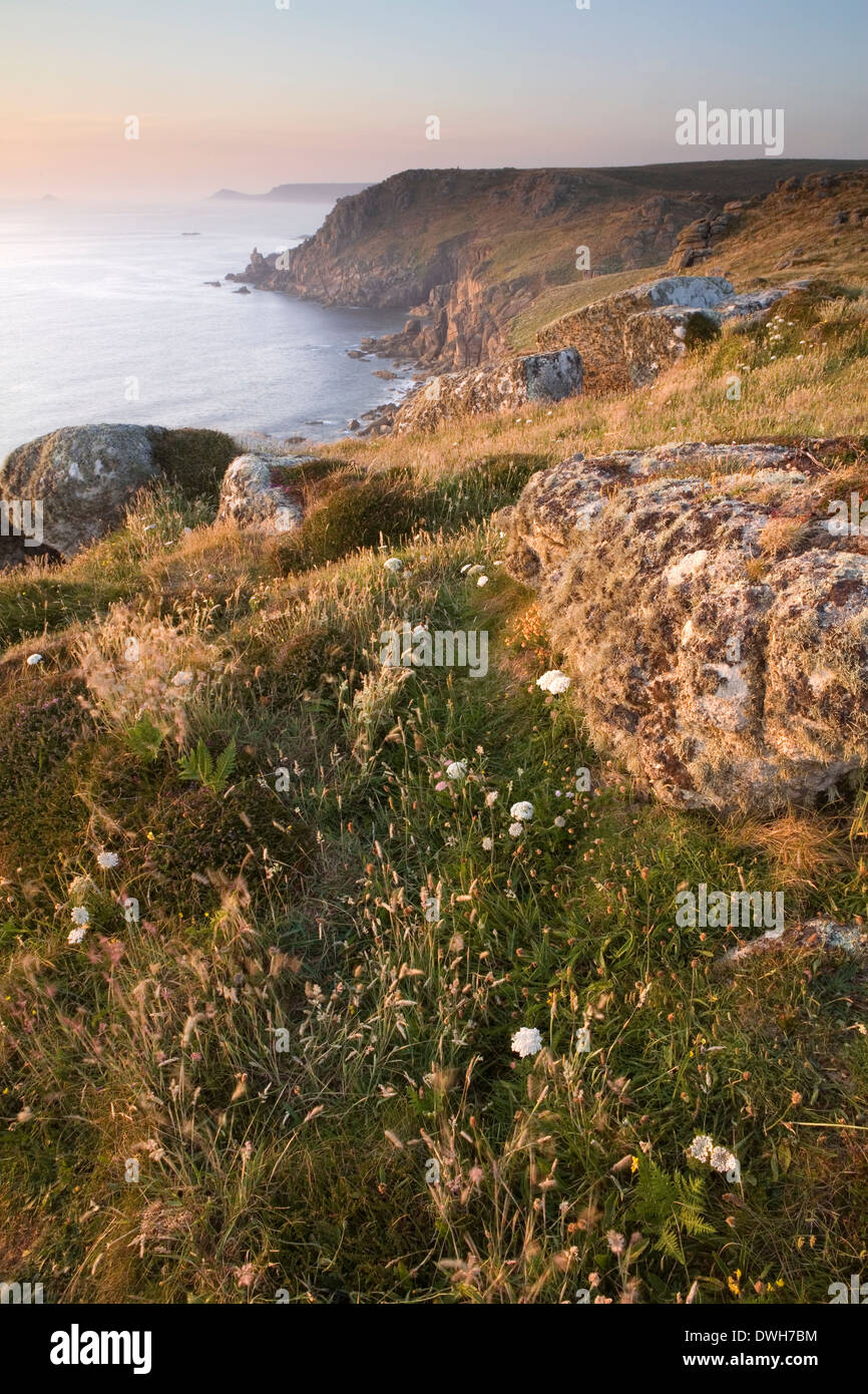 Un vago sole tramonta su Sennen Cove al Land's End, Cornwall in estate. Foto Stock