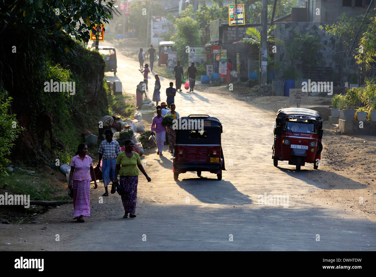 Pedoni e tuk tuk taxi a motore in strada, la mattina presto in Ella, Sri Lanka Foto Stock
