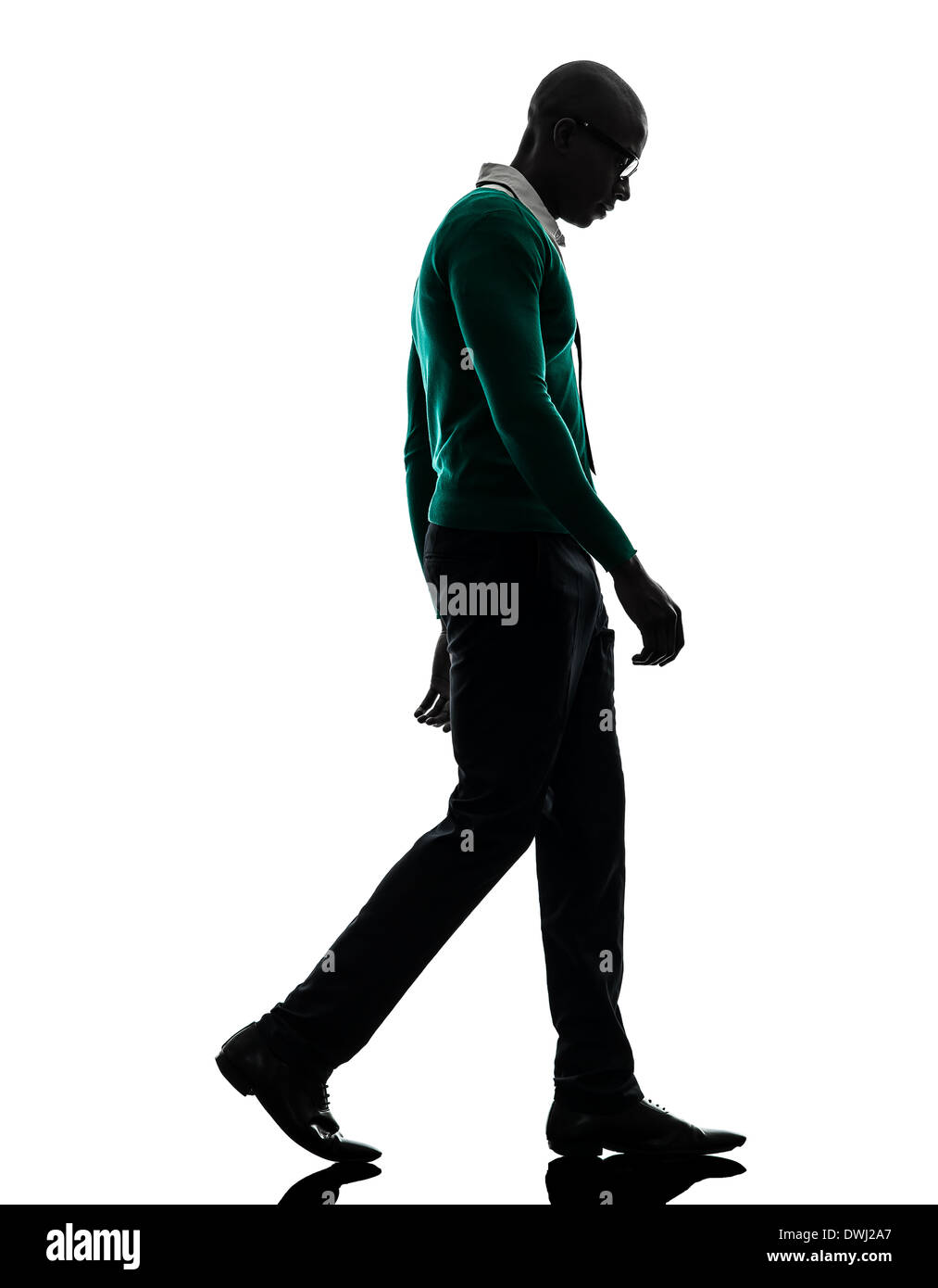 Uno nero africano uomo a camminare guardando giù triste in silhouette studio su sfondo bianco Foto Stock