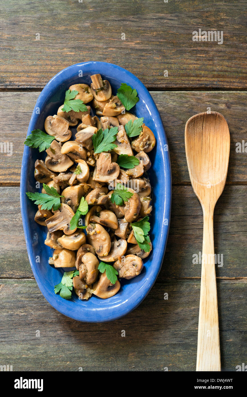 I funghi cotti in un vassoio di blu e di un tavolo di legno Foto Stock