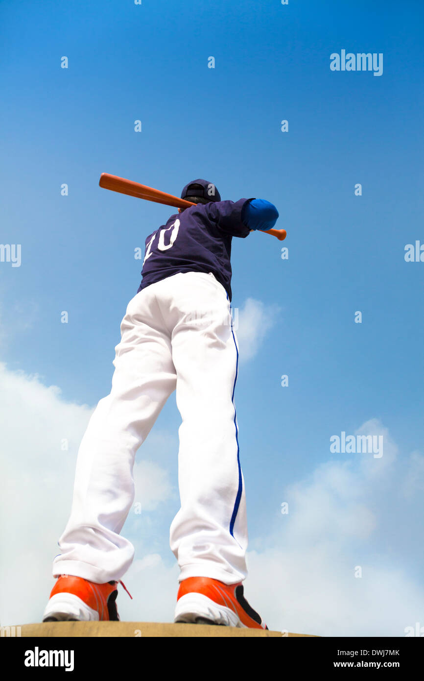 Giocatore di baseball tenendo un bat con cielo blu per esterno Foto Stock