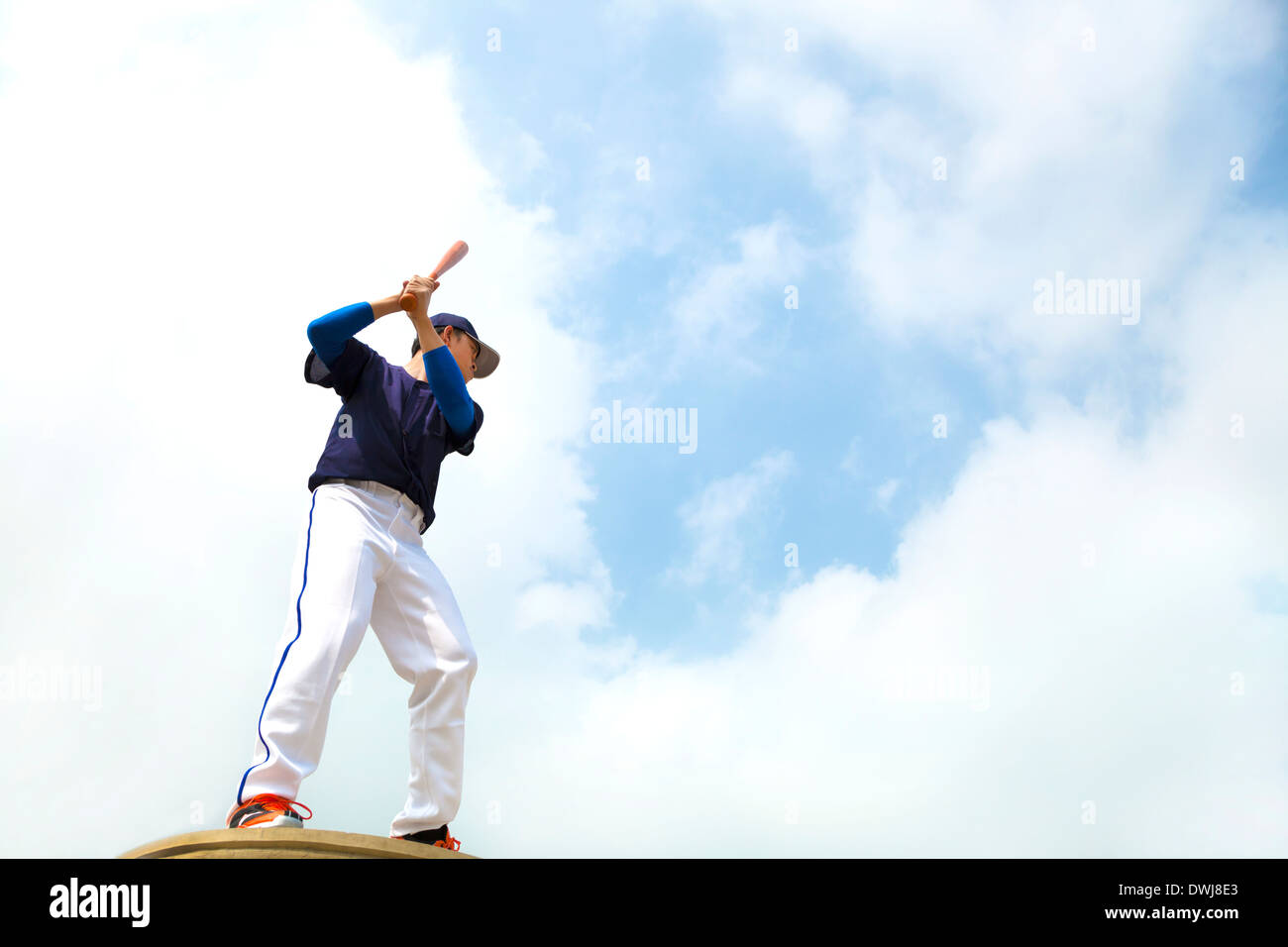 Giocatore di baseball effettuare una posa per colpire la palla con il cielo blu Foto Stock