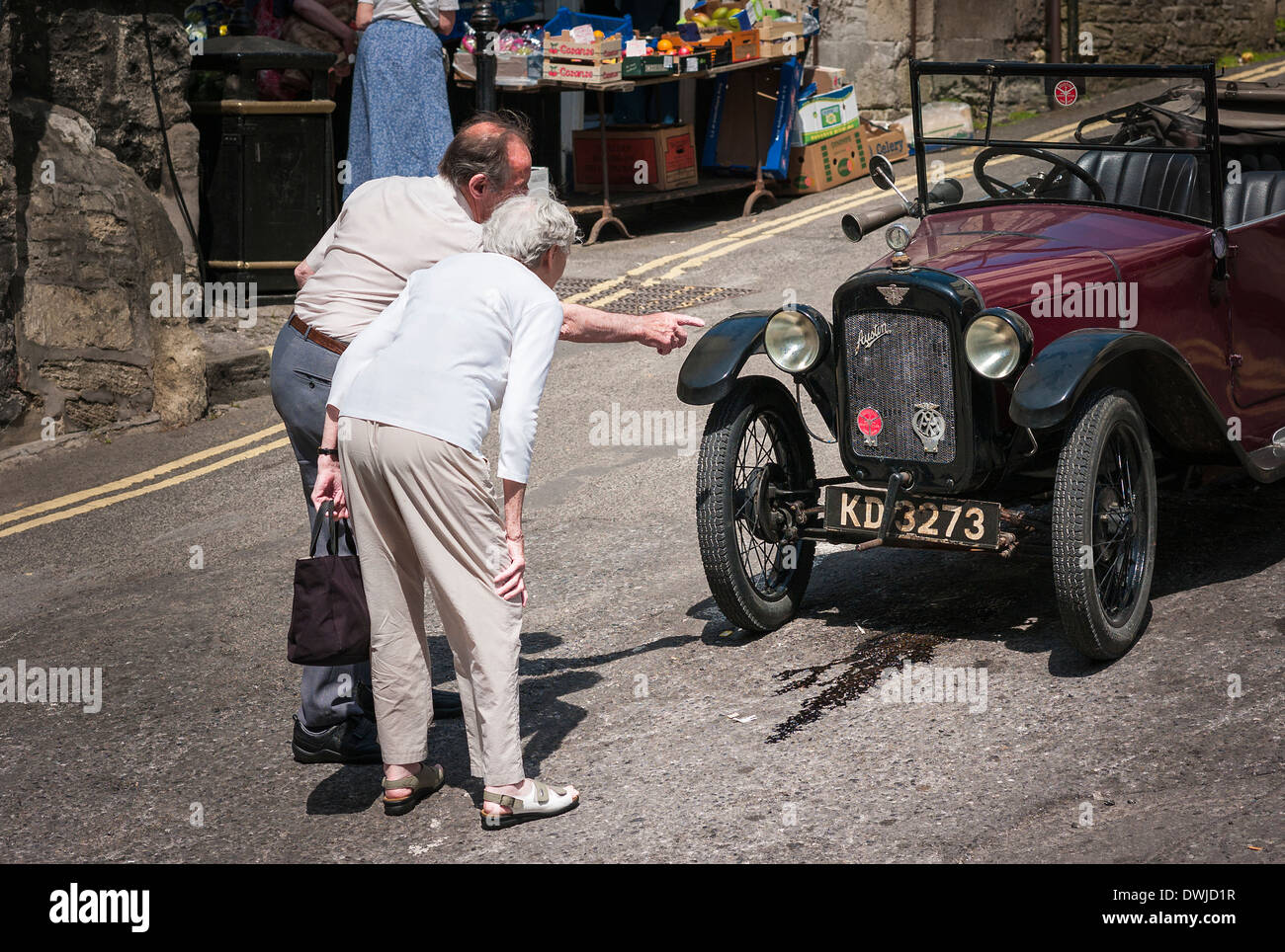 Coppia di anziani discutendo old Austin 7 open tourer auto parcheggiate in una città Wiltshire. Foto Stock