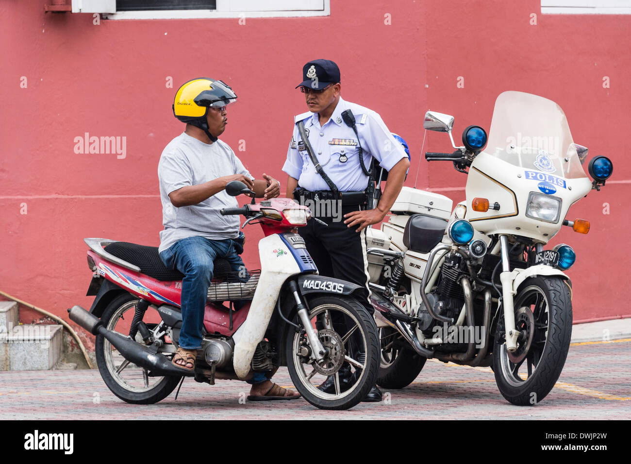 Un poliziotto parla con un motore ciclista in Malacca, Malesia Foto Stock