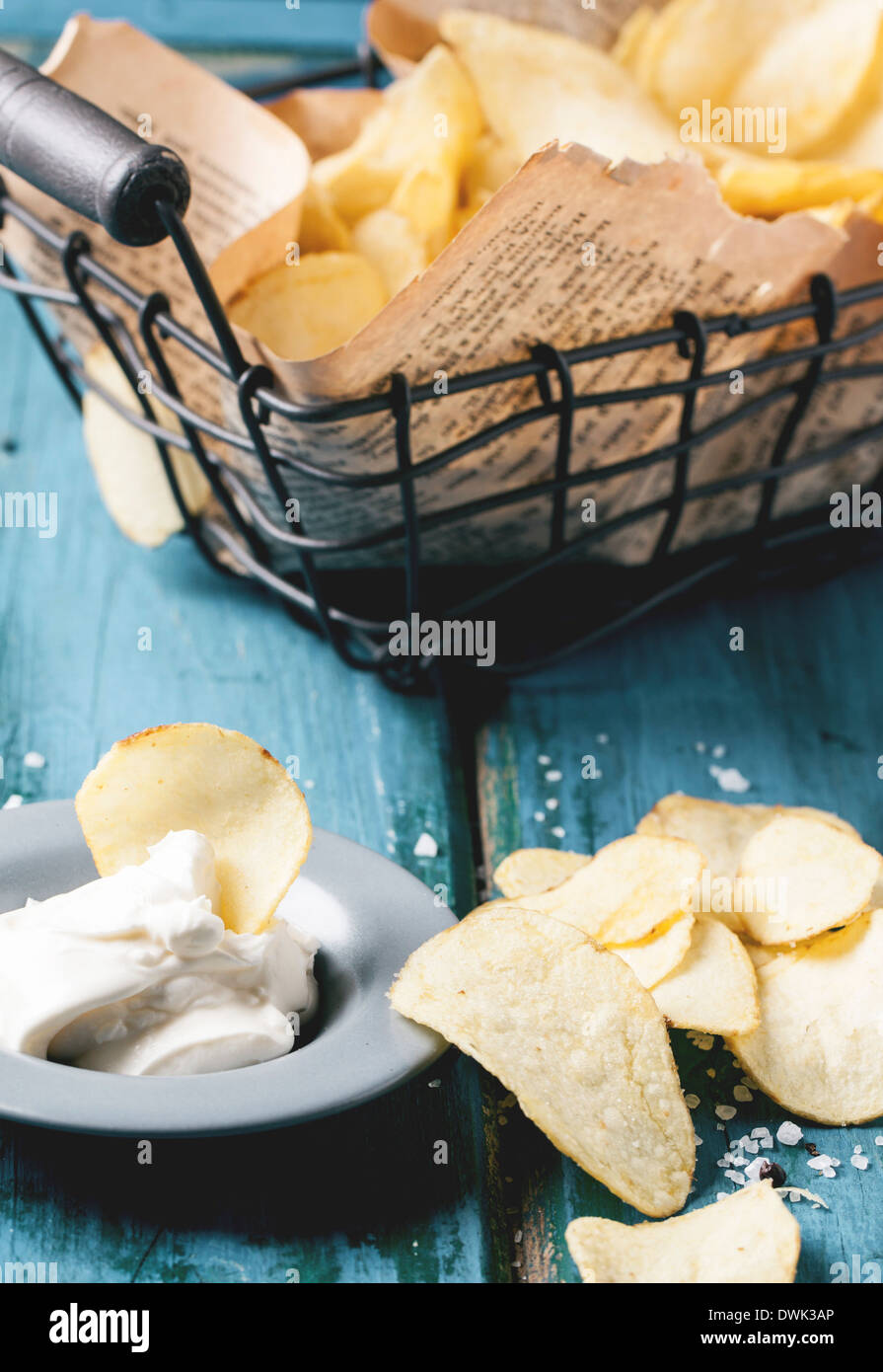 Cestino con patate fritte con piastra di salsa e sale di mare blu su un tavolo di legno. Foto Stock