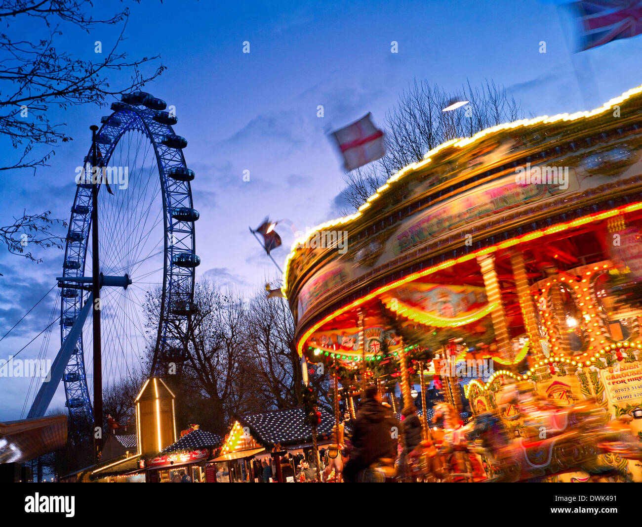 Parco di divertimenti invernali ride con il London Eye dietro al crepuscolo Jubilee Gardens South Bank di Londra Inghilterra Foto Stock