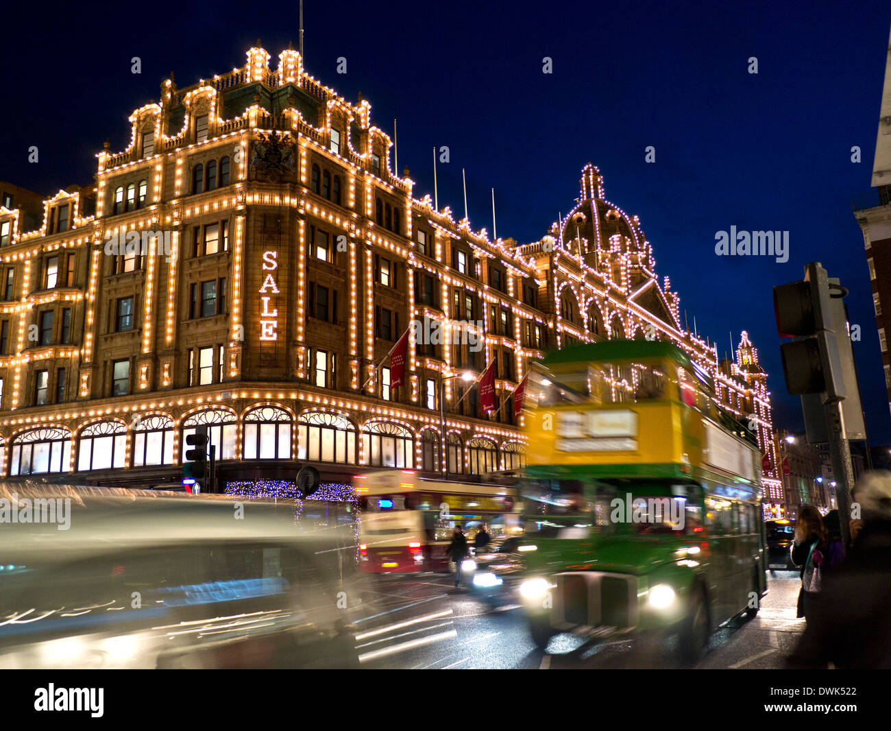 IL GRANDE magazzino DI VENDITA Harrods di notte con il cartello 'ale' per gli acquirenti E vintage retro Harrods marchio tour in autobus e traffico di passaggio Knightsbridge London SW1 Foto Stock