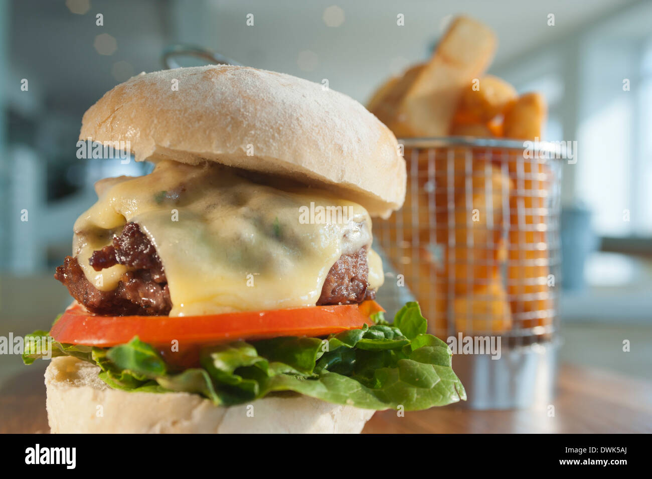 Beefburger con un ordine di patatine fritte o scaglie di patate, con un riempimento di insalata con formaggio fuso e pancetta come un extra. Foto Stock