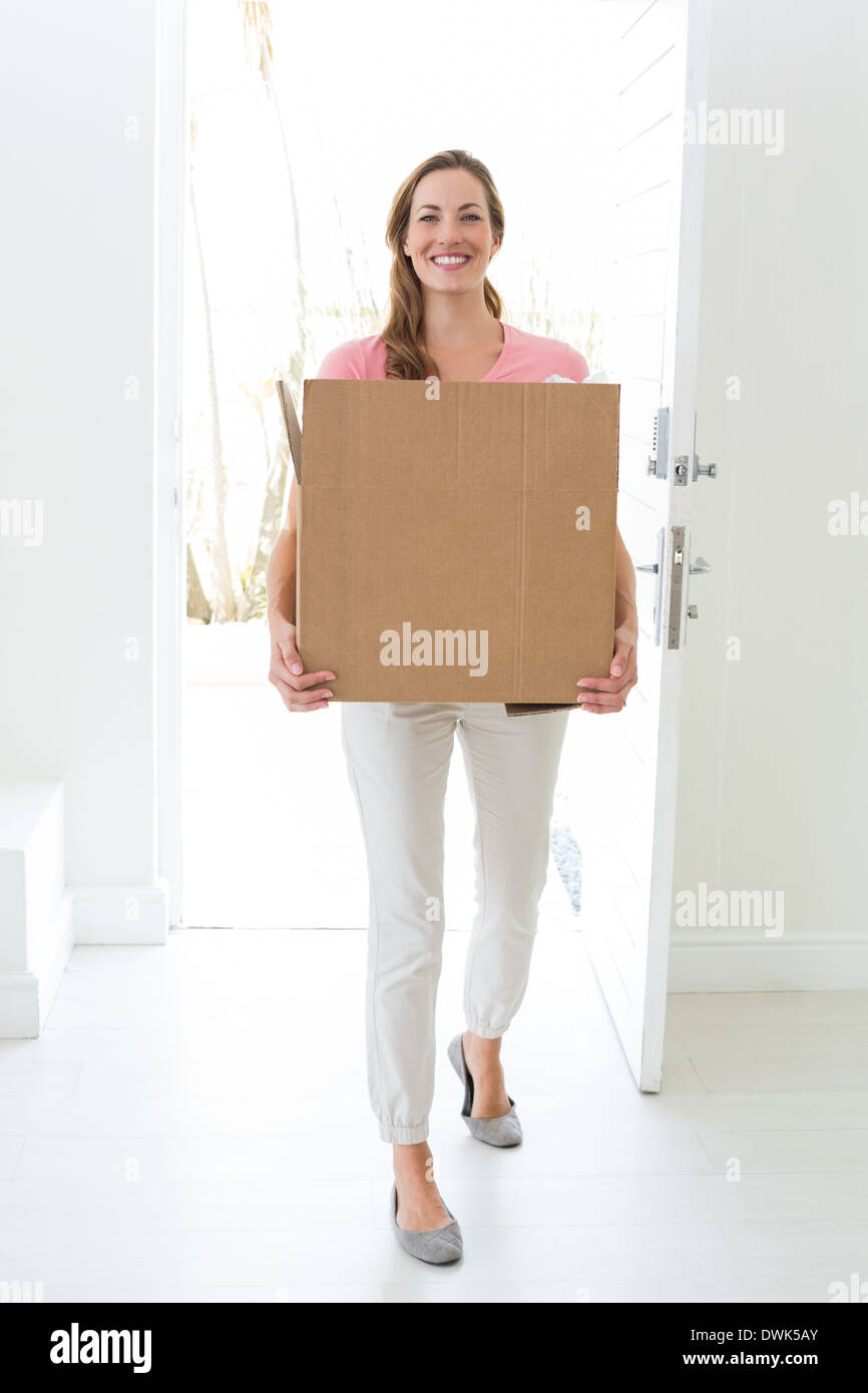 La donna che porta una scatola di cartone in casa nuova Foto Stock