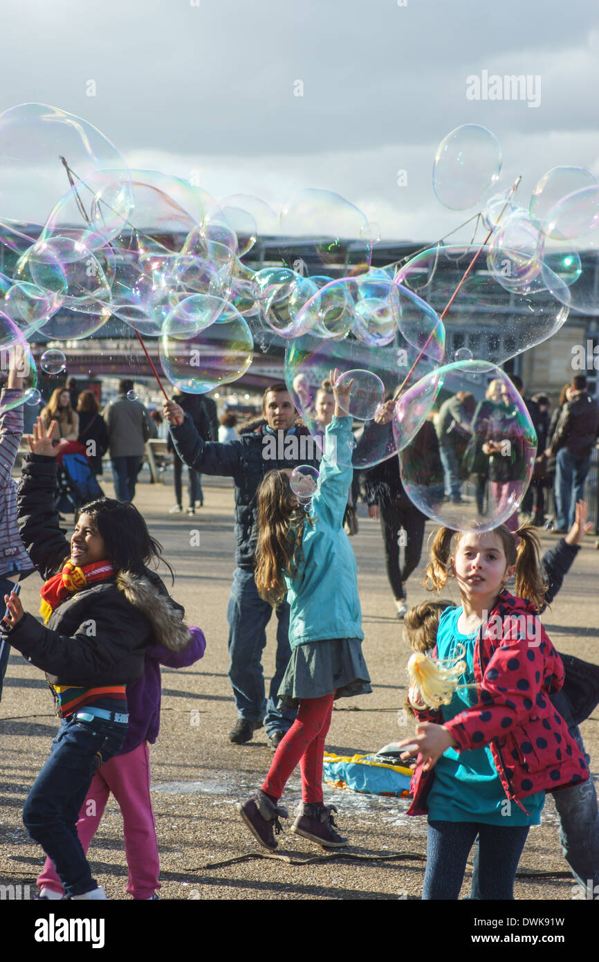 Street intrattenitore soffia bolle per bambini London South Bank. Bambini che giocano con bolle Foto Stock