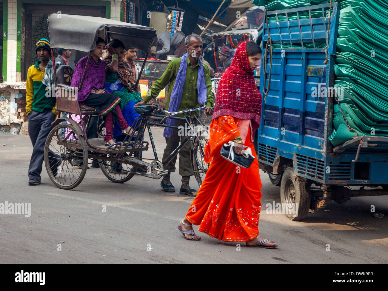 Agra, India. Scena di strada, Kinari Bazar Area. Donne Equitazione in un rickshaw. Donna in Sari a piedi. Foto Stock