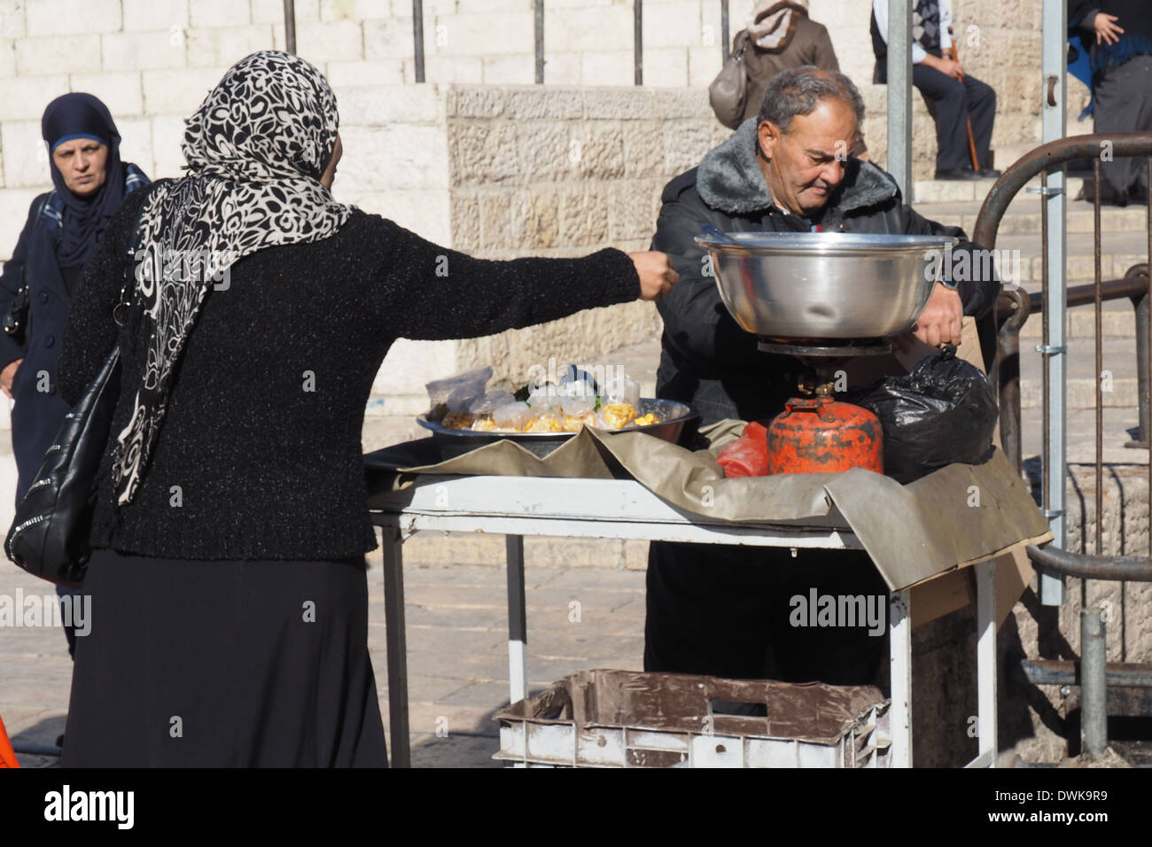 La donna araba acquisto di fagioli cotti da un venditore ambulante fuori porta di Damasco, città vecchia di Gerusalemme Foto Stock