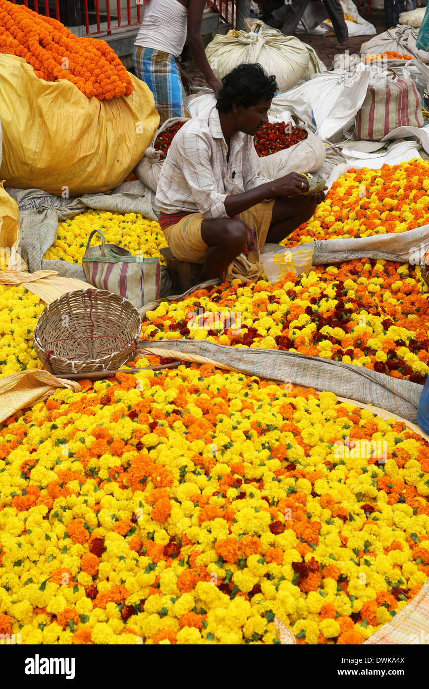 Persone che acquistano e vendono fiori e ghirlande presso il mercato dei fiori accanto a un binario ferroviario in Kolkata, India Foto Stock