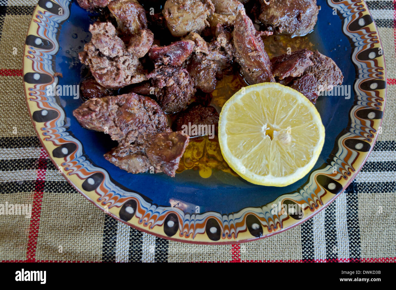 Porzione di fegato di pollo arrosto con burro e limone nella piastra di argilla Foto Stock