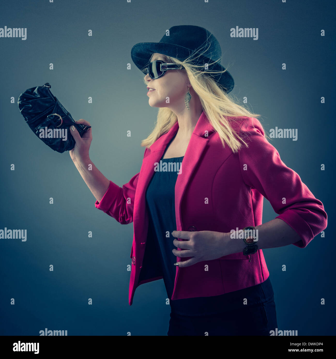 Urbano donna matura che indossa un paio di occhiali da sole e cappello, studio shot Foto Stock