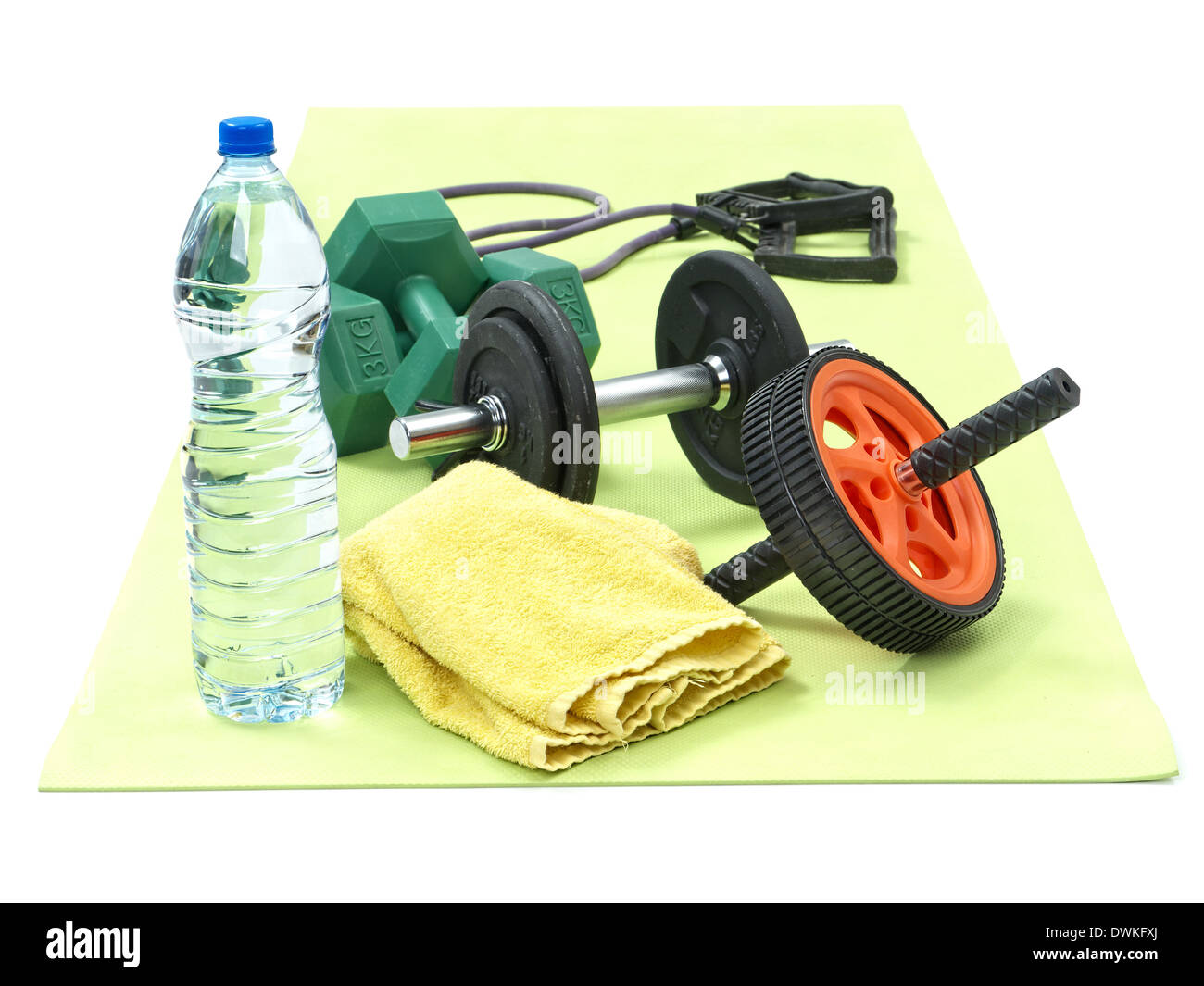 Set di dumbbels, esercizio ruota, cavo, asciugamano e una bottiglia di acqua sul verde tappetino fitness Foto Stock