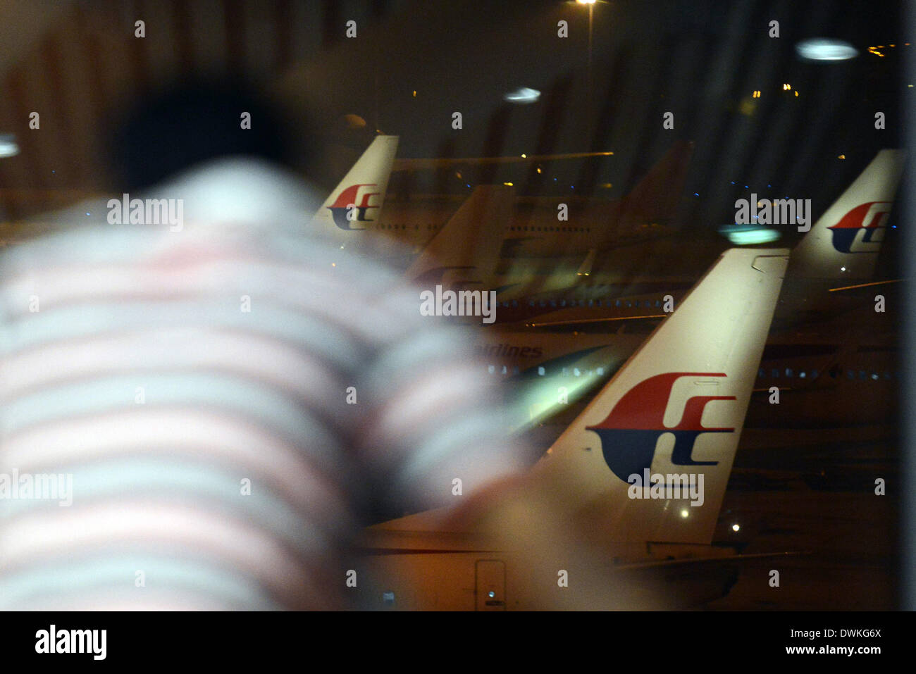 Kuala Lumpur, Malesia. Decimo Mar, 2013. Un uomo si affaccia da una galleria di visualizzazione come la Malaysia Airlines aeromobili si siede su asfalto presso l'Aeroporto Internazionale di Kuala Lumpur in Sepang, al di fuori di Kuala Lumpur, Malesia, Sabato, 10 marzo 2014. L'operazione di ricerca per la mancanza della Malaysia Airlines MH370 che ha coinvolto 34 aeromobili e 40 navi provenienti da diversi paesi a copertura di un 50-miglio nautico raggio dal punto il piano sparito dalle schermate del radar tra la Malaysia e Vietnam continua dopo la sua scomparsa dal sabato. Gli esperti dicono che le possibili cause del crash apparente includono un explo Foto Stock