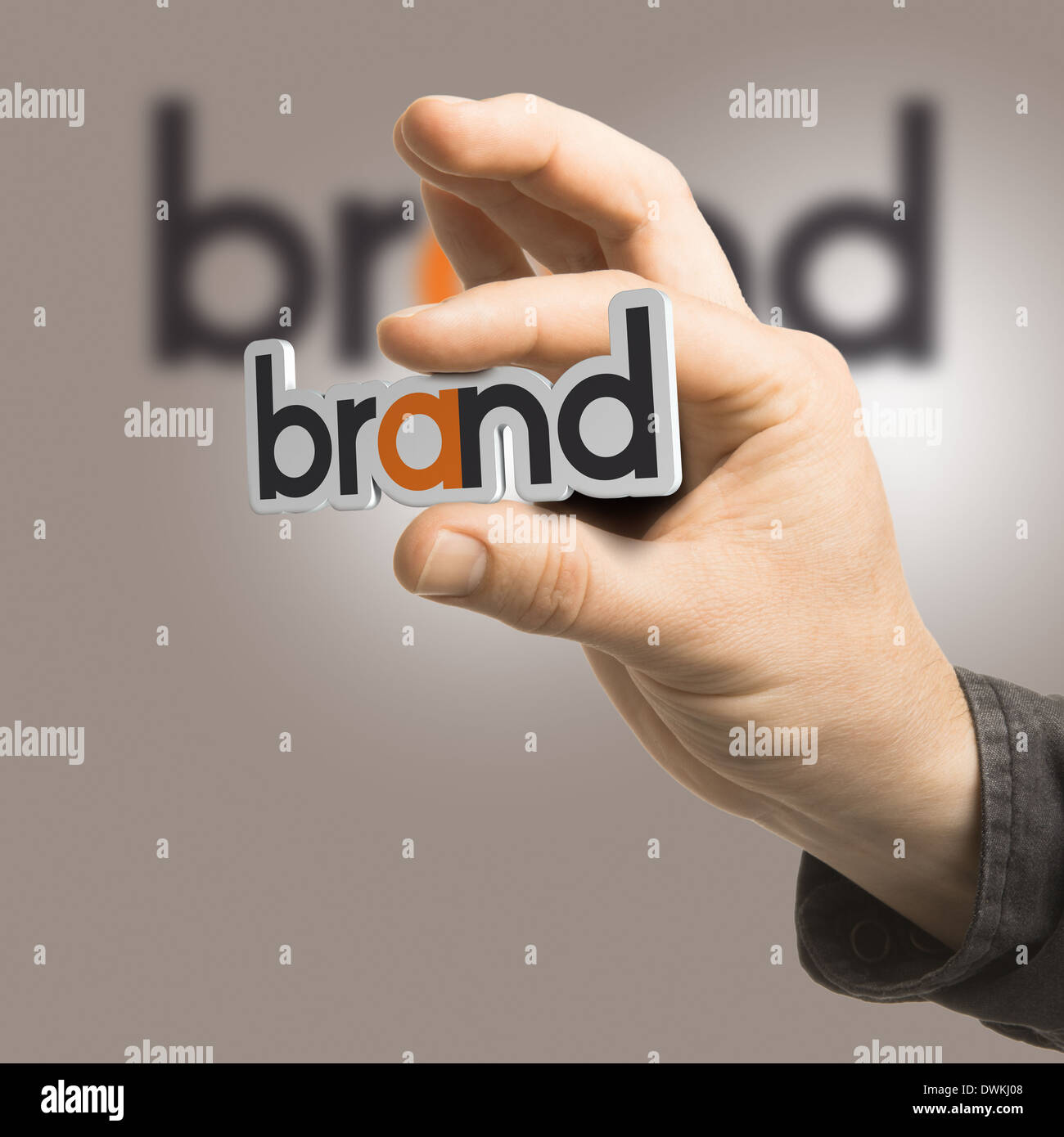 Una mano che tiene la parola brand su un sfondo beige. Foto Stock