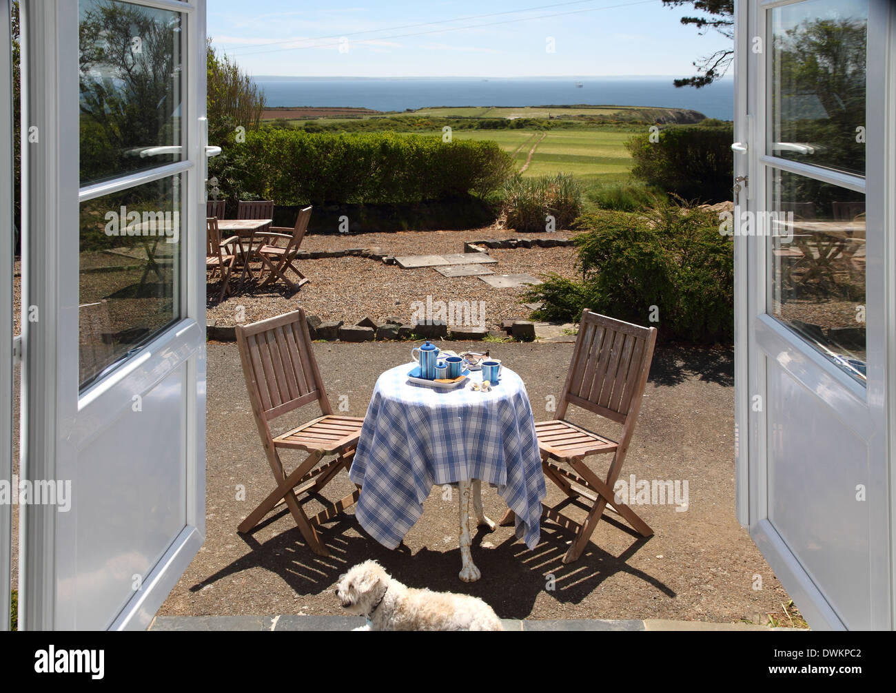 Guardando attraverso le porte francesi per visualizzare. Visualizzazione include il tavolo della colazione,dog,i campi e il mare. Foto Stock