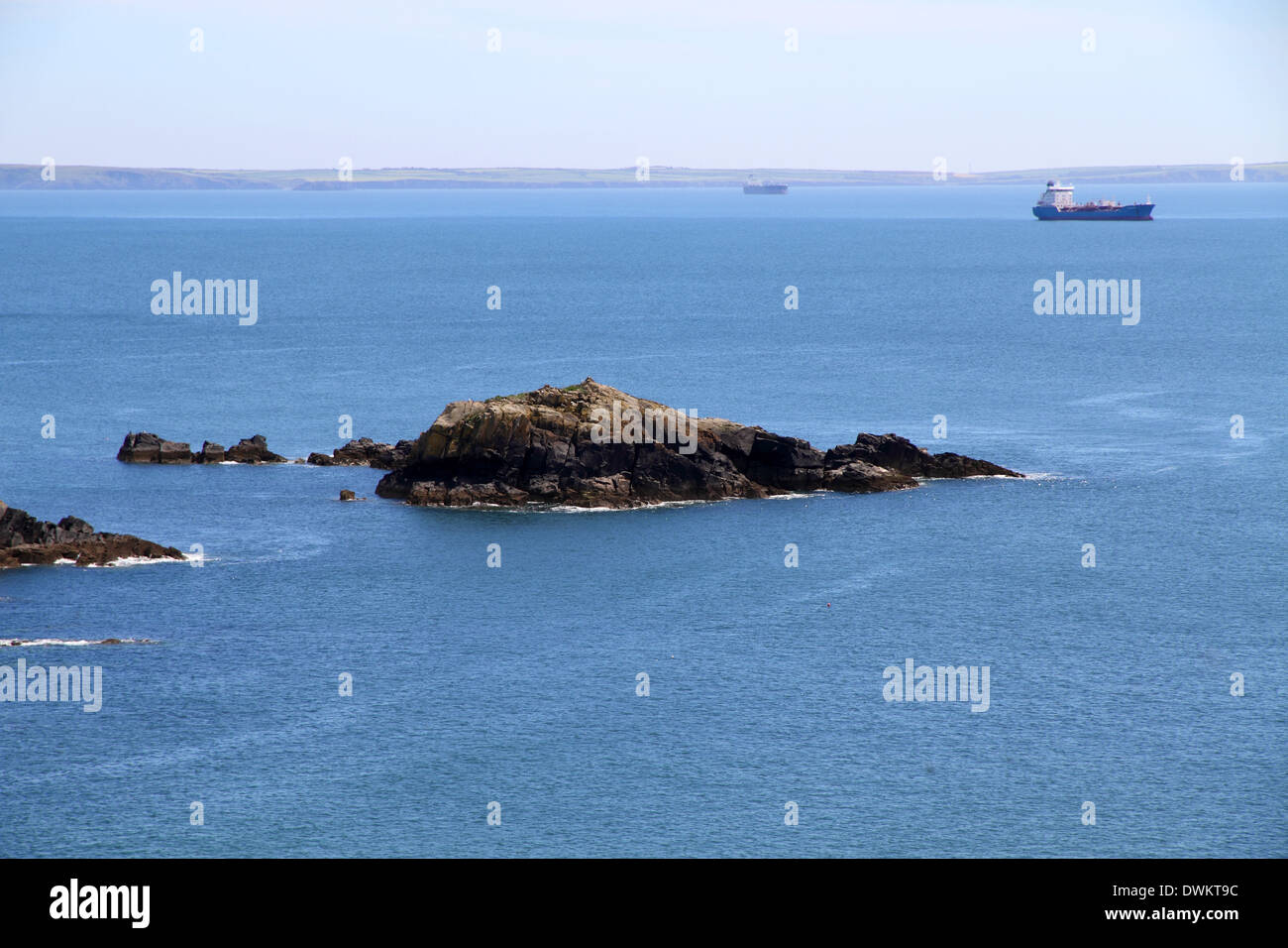 Vista del blu del mare e del cielo con rocce e una petroliera ancorata Foto Stock