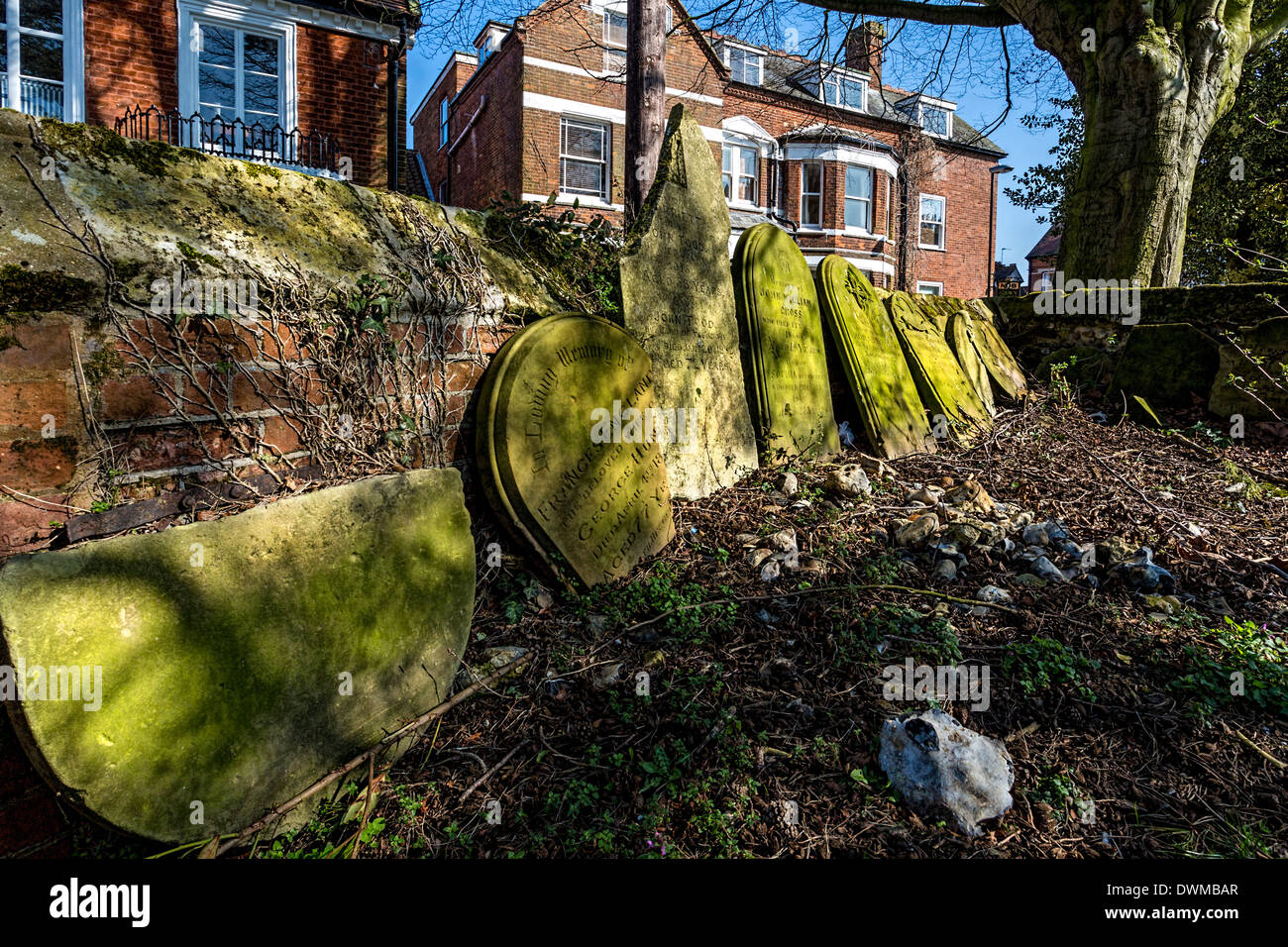 Lapidi appoggiato un basso muro di mattoni in Abbazia motivi a Wymondham, Norfolk, Regno Unito. Foto Stock