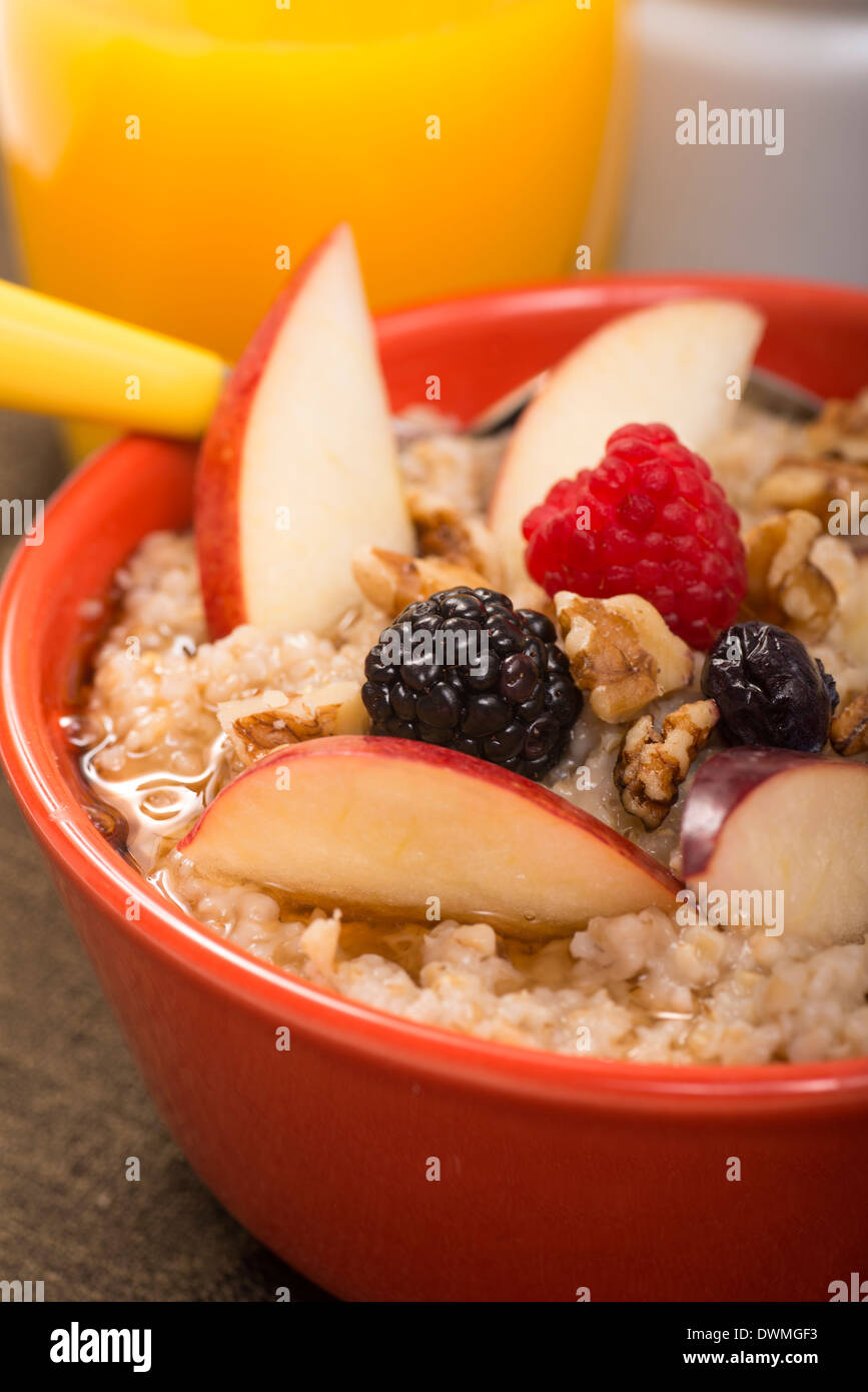 Ciotola di deliziose acciaio tagliati di avena con frutta fresca, il miele e il succo di arancia Foto Stock