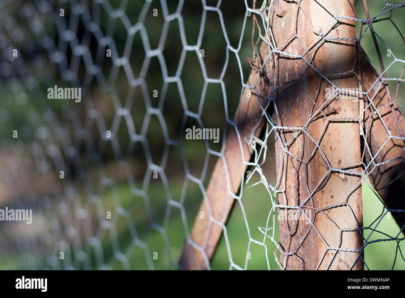 Metallo arrugginito corner palo da recinzione visibile dietro un filo catena collegamento recinto Foto Stock