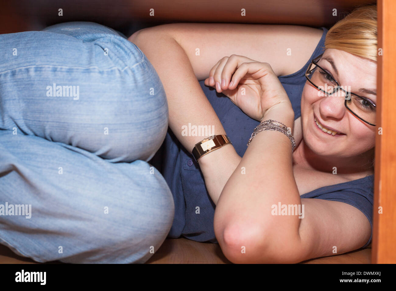 Primo piano della donna divertente che si nasconde sotto la tabella. Foto Stock