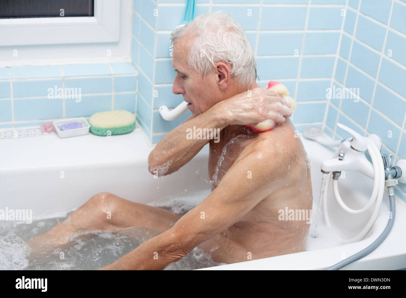 Senior lavaggio uomo il suo corpo con spugna di sapone in bagno. Foto Stock