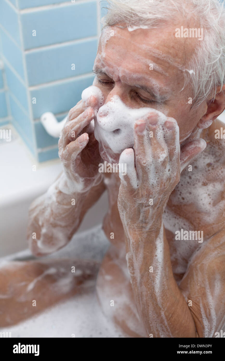 Senior lavaggio uomo il suo corpo con sapone in bagno. Foto Stock