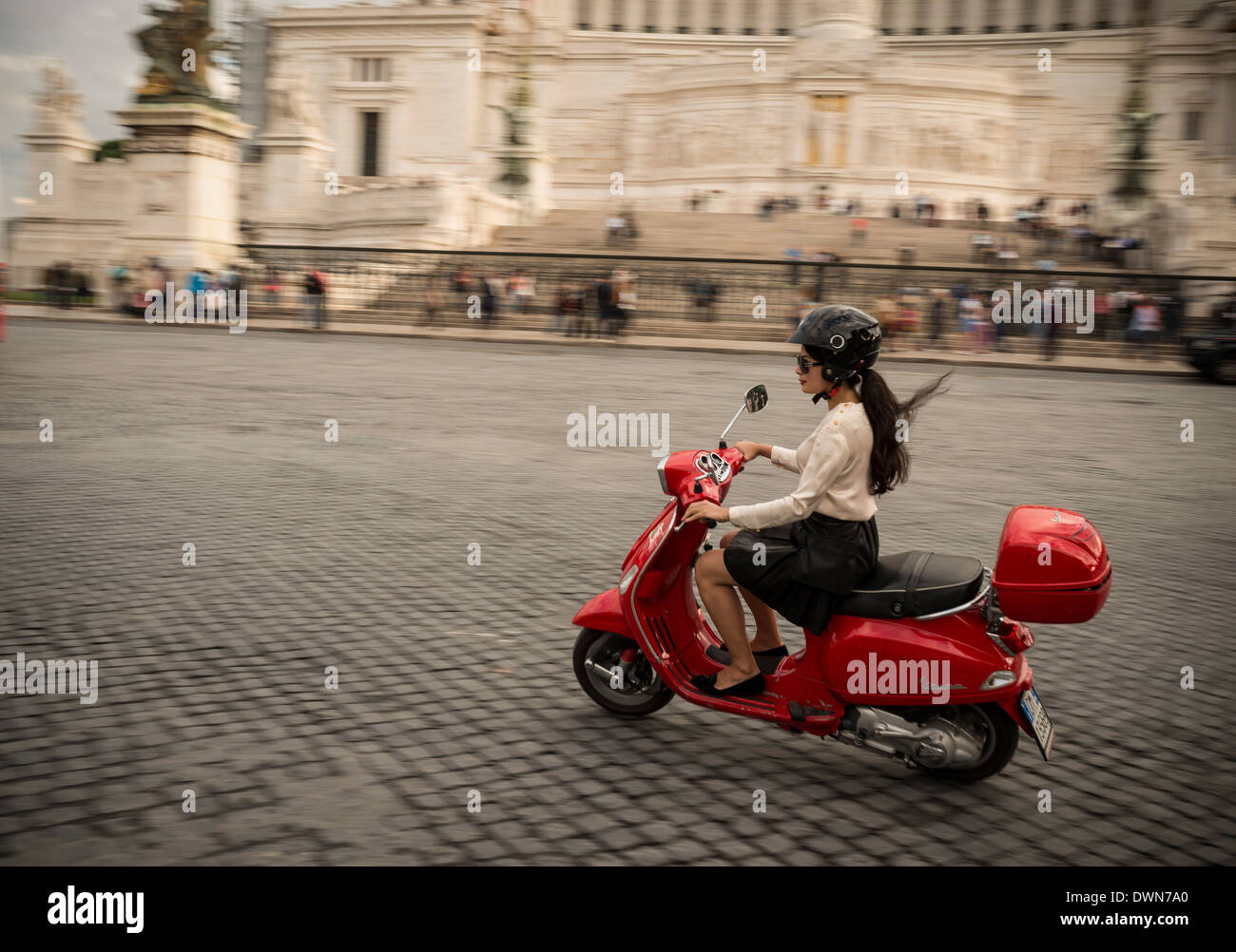 Giovane donna riding Vespa ciclomotore attraverso strade nella parte anteriore del monumento a Vittorio Emanuele, Roma, Lazio, l'Italia, Europa Foto Stock