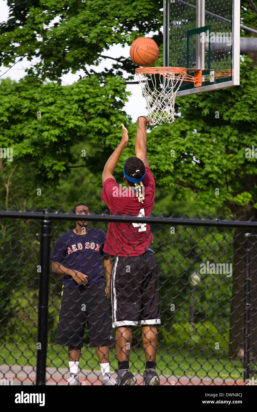 Due uomini giocare a basket in un parco pubblico Foto Stock