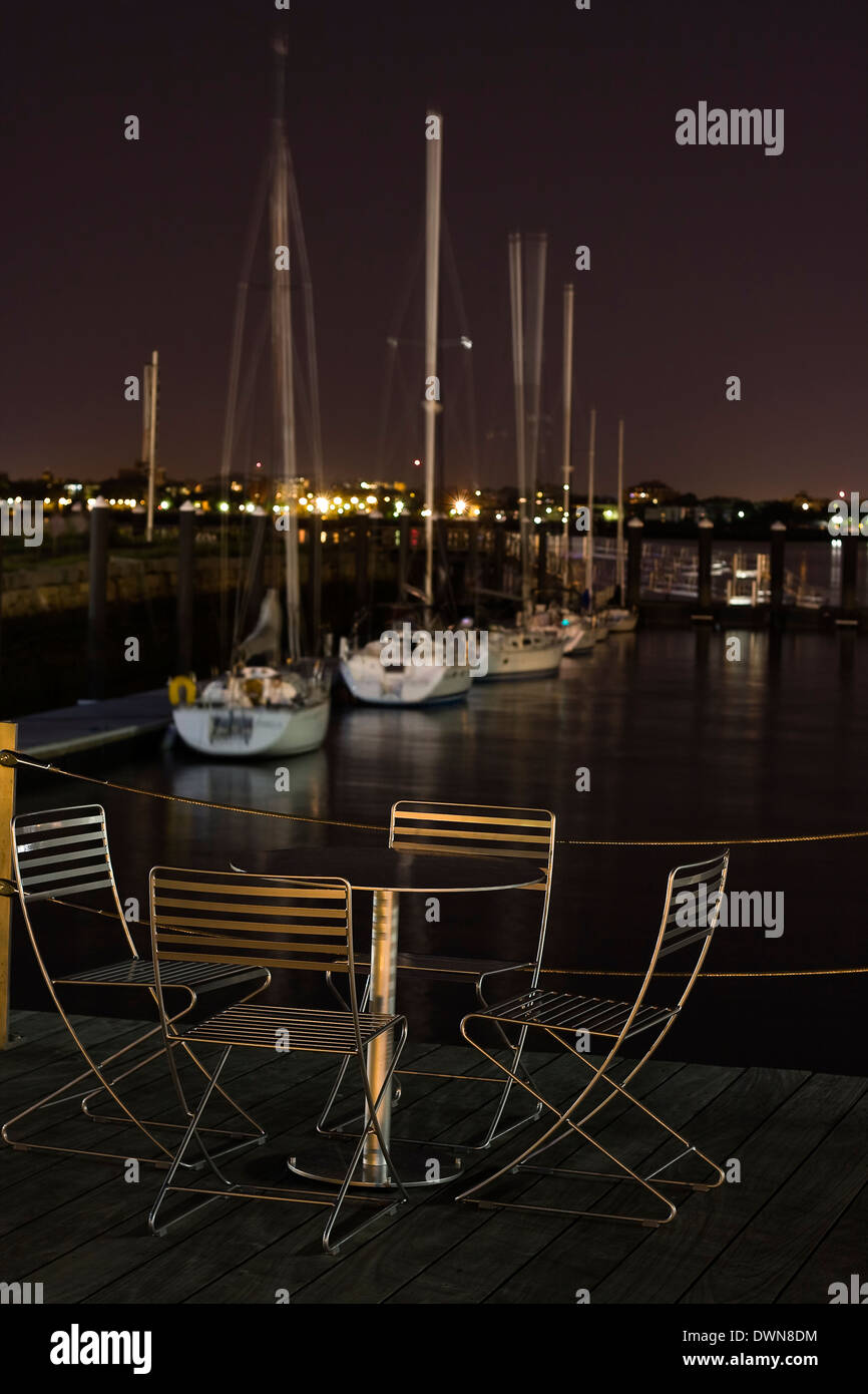 Outdoor tavolo e quattro sedie lungo Boston's Harborwalk affacciato su barche a vela ormeggiata al molo della ventola nella Marina di Porto di Boston Foto Stock