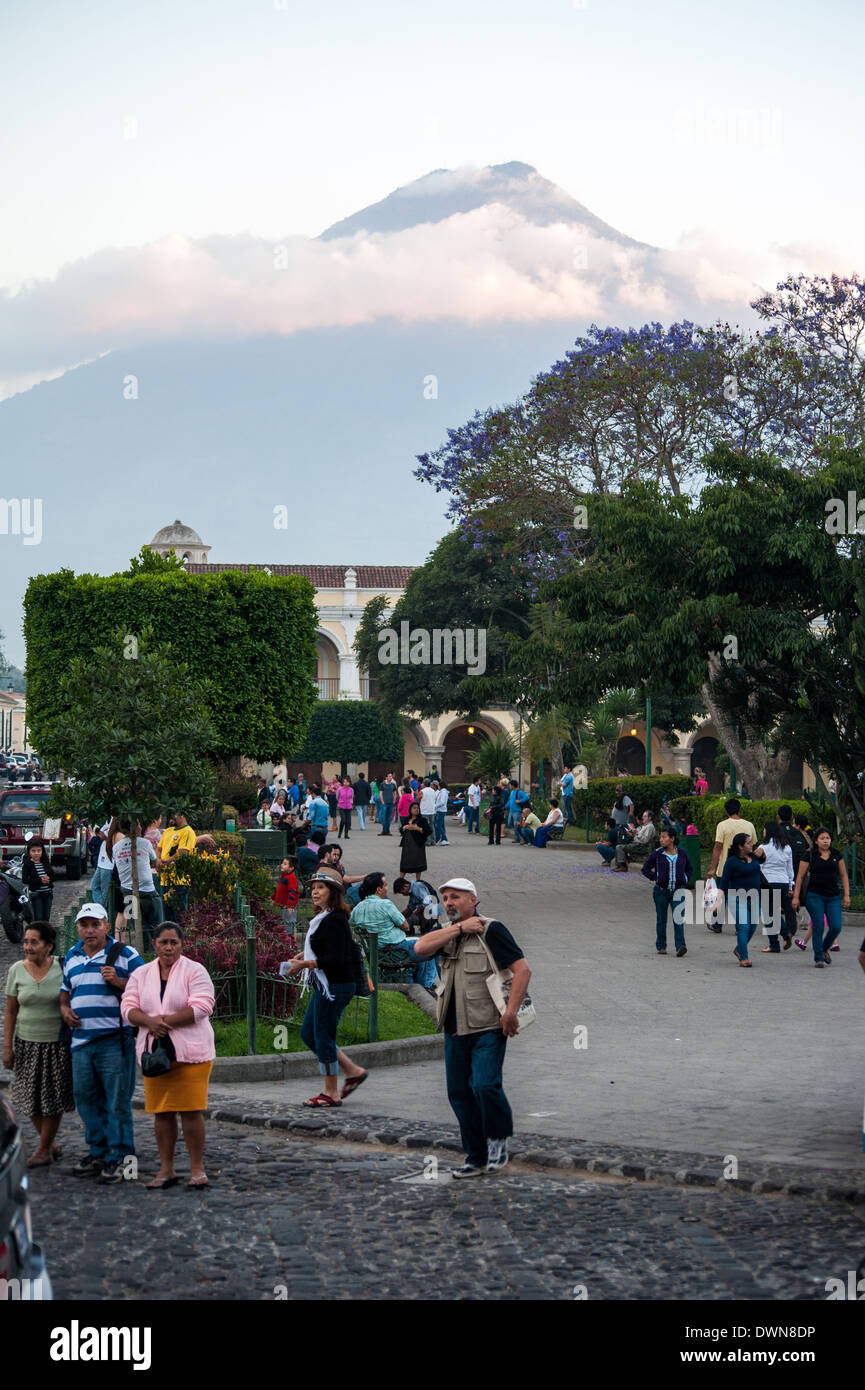 La gente a piedi attraverso il Parque Central in Antigua Guatemala con Volcán de Agua comandando la visualizzazione dello sfondo. Foto Stock