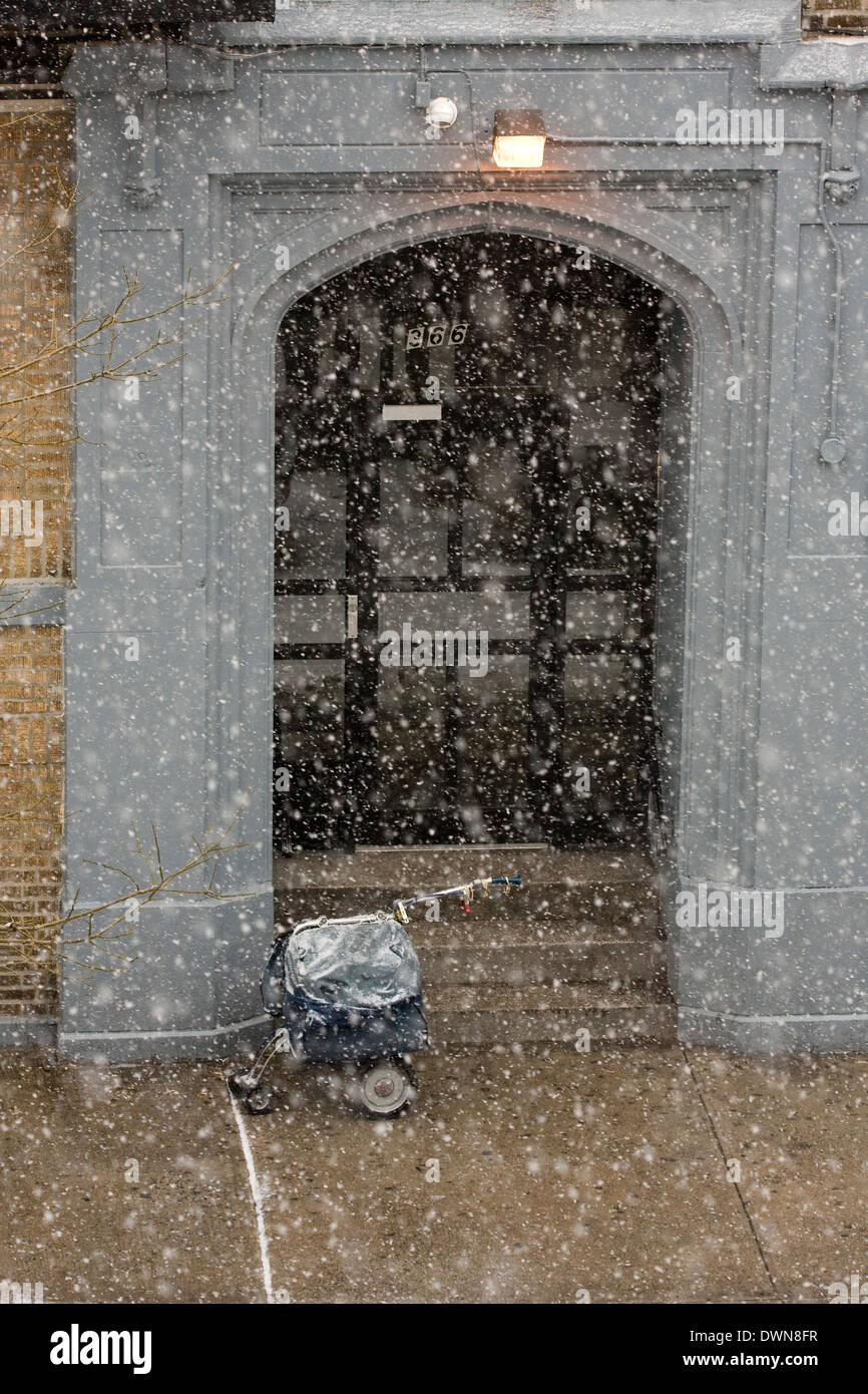 A New York City Mailman del carrello a ruote sul marciapiede durante una tempesta di neve Foto Stock