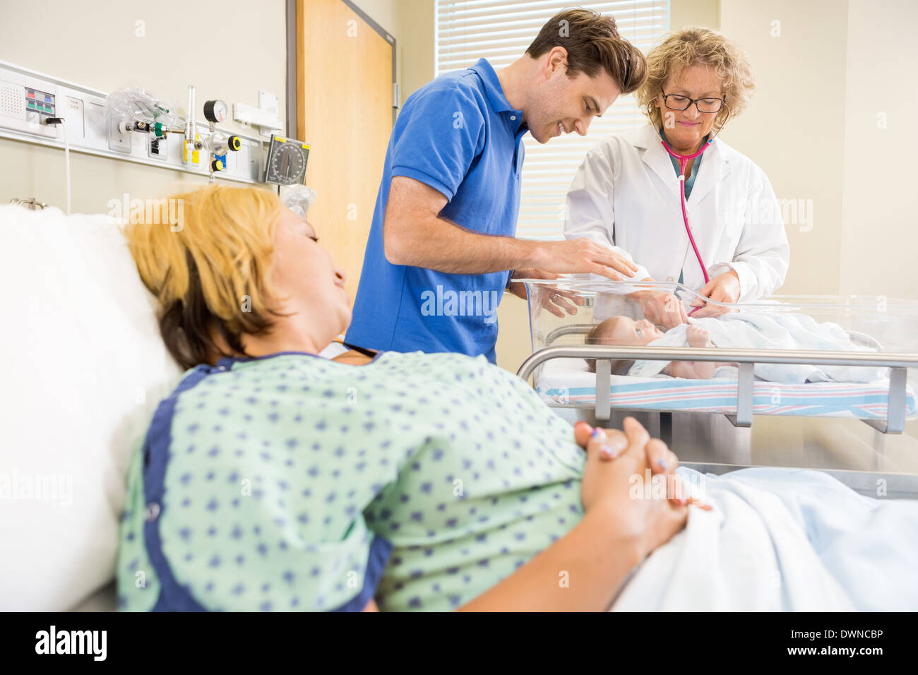 Medico esaminando neonato mentre i genitori guardando il suo Foto Stock