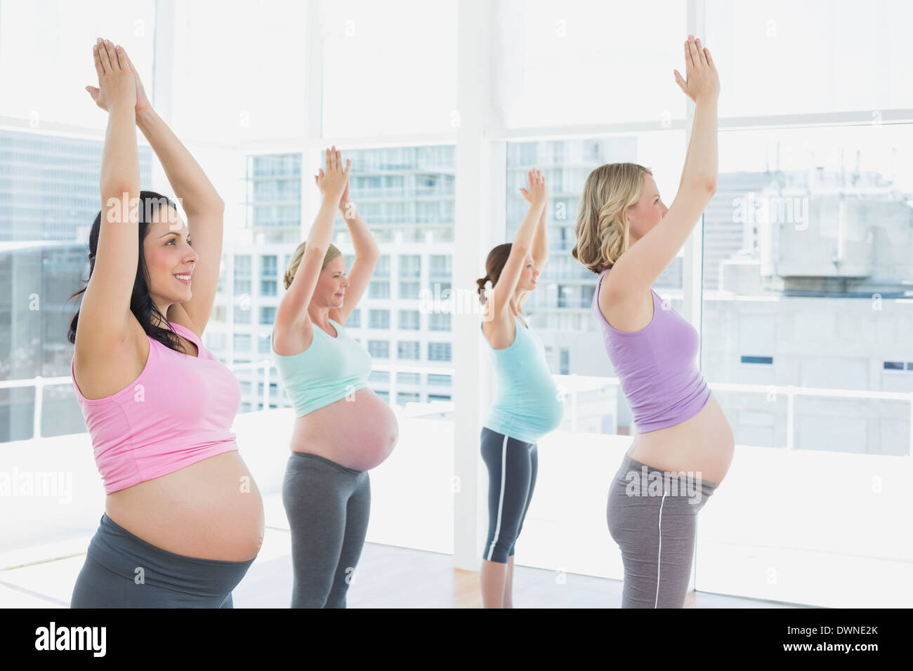 Felici le donne in stato di gravidanza in corso di yoga in piedi in posa ad albero Foto Stock