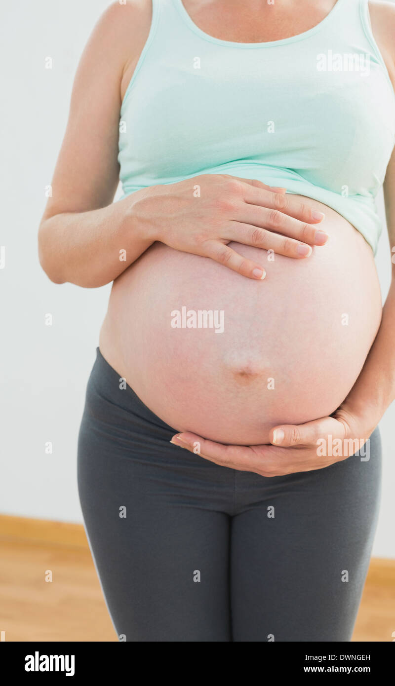 Donna incinta mentre tiene il suo grande baby bump Foto Stock