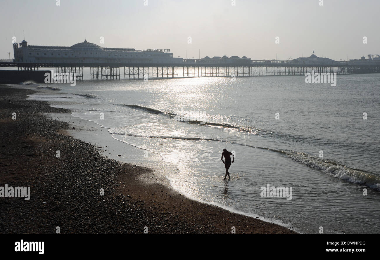 Un inizio di mattina nuotatore emerge dal mare come egli rende la maggior parte delle belle giornate di sole sulla spiaggia di Brighton Foto Stock