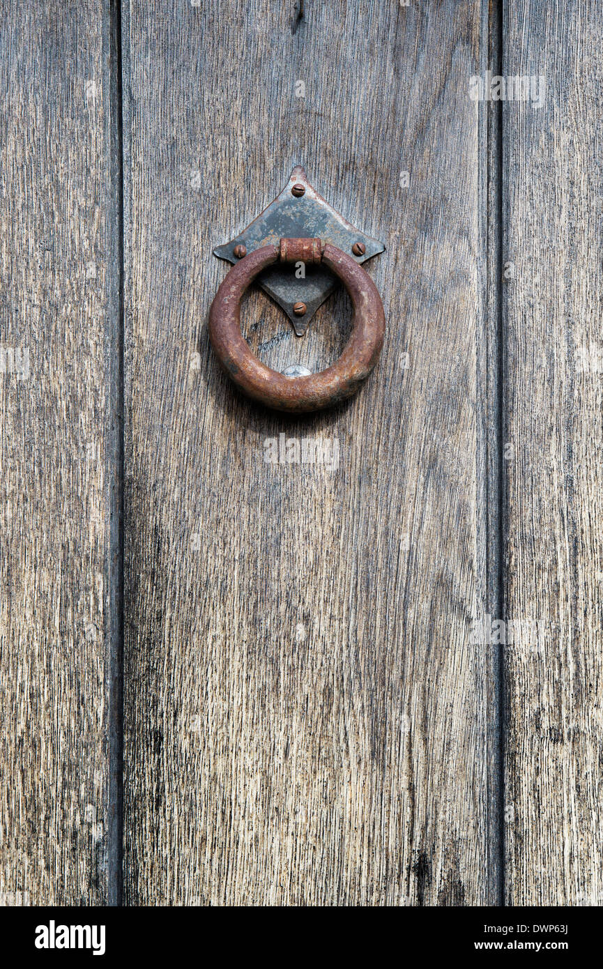 Arrugginiti in ferro battuto respingente porta su una vecchia quercia Legno porta in Cotswolds, Inghilterra Foto Stock