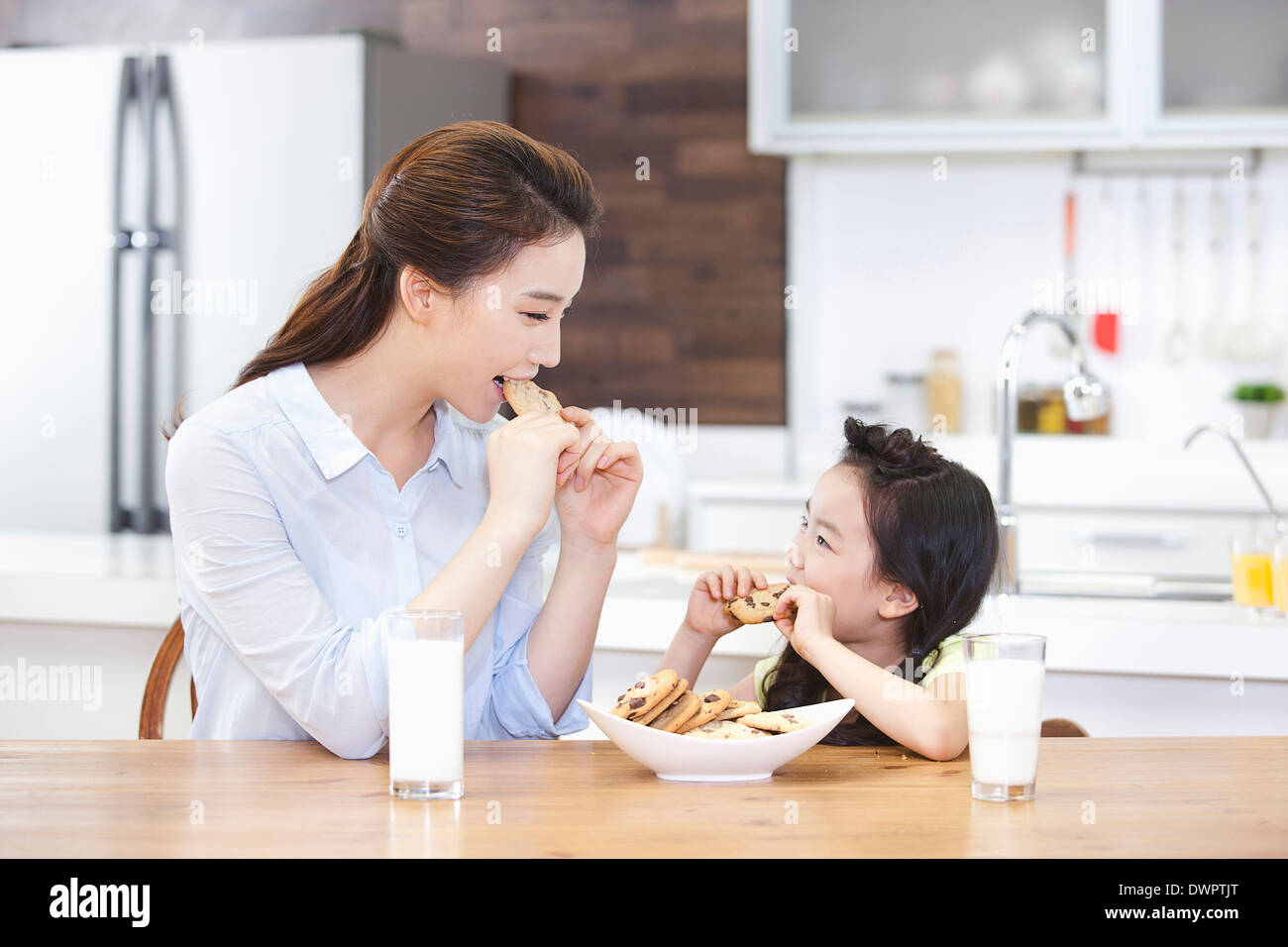 Una madre e una figlia godendo i cookie in cucina Foto Stock
