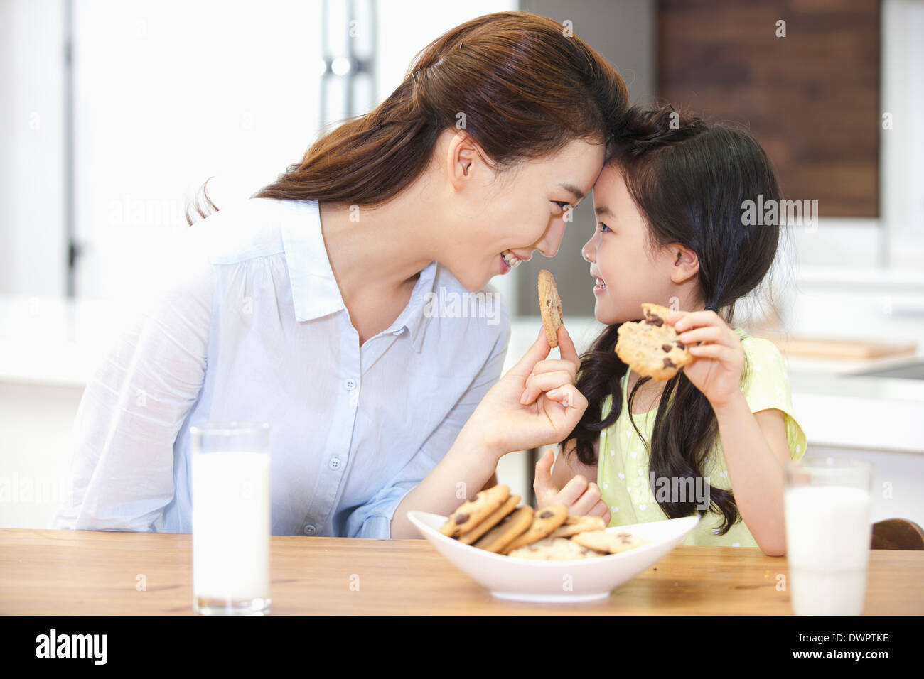 Una madre e una figlia godendo i cookie in cucina Foto Stock