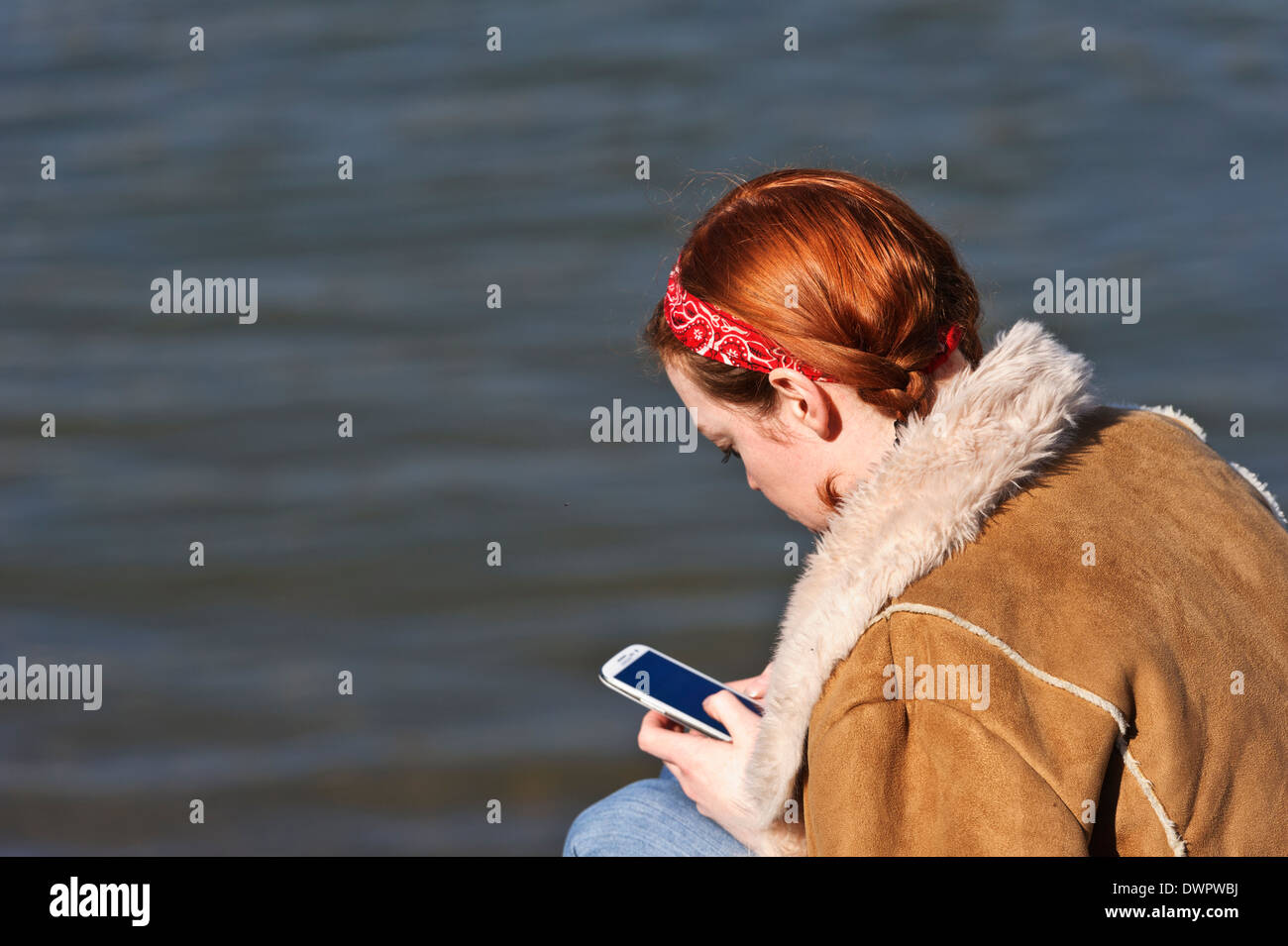 Giovane donna texting occupato sul suo telefono mobile a Londra, Inghilterra, Regno Unito. Foto Stock