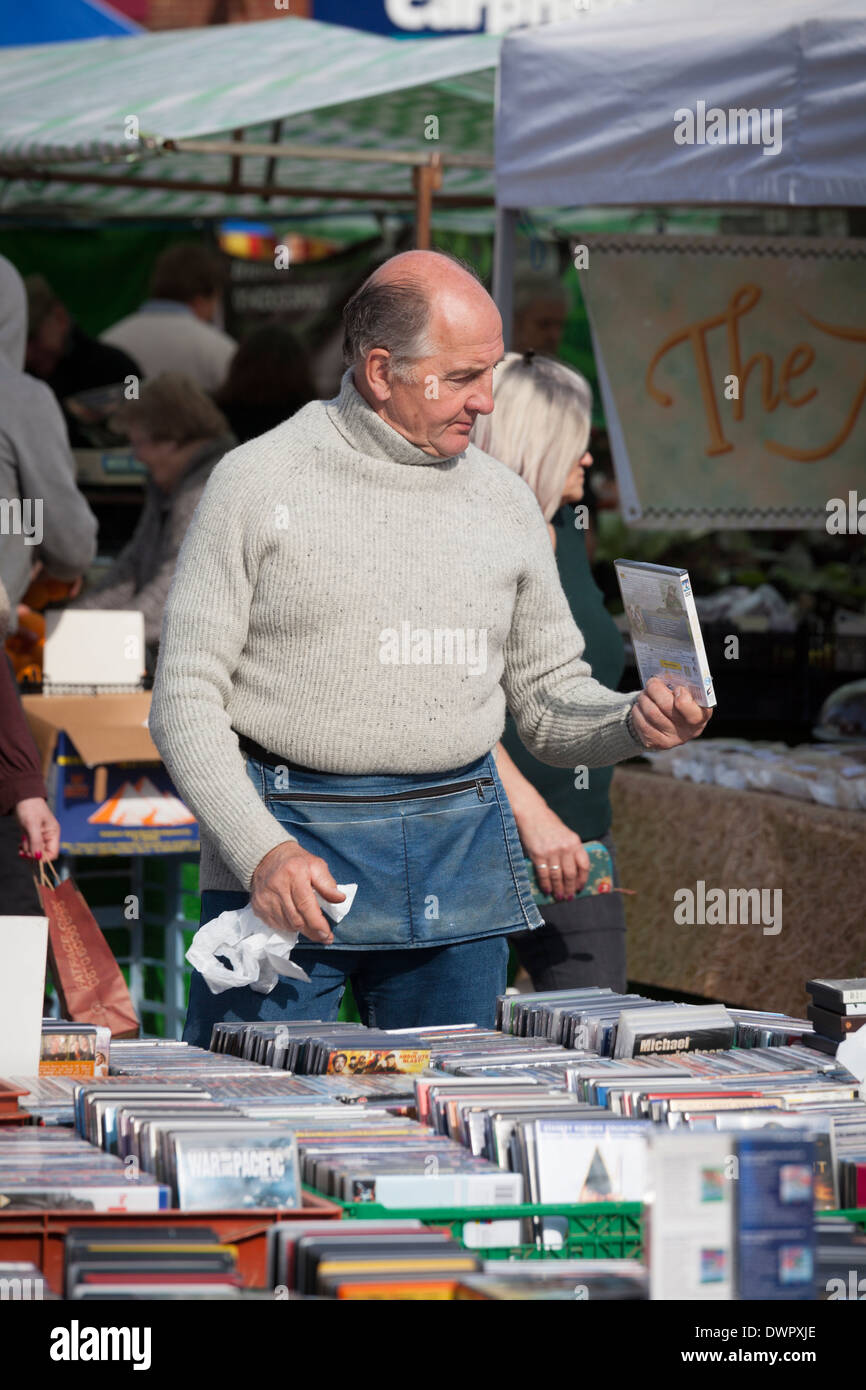 Commerciante di mercato con custodia denaro vendendo i DVD dal mercato in stallo. Foto Stock