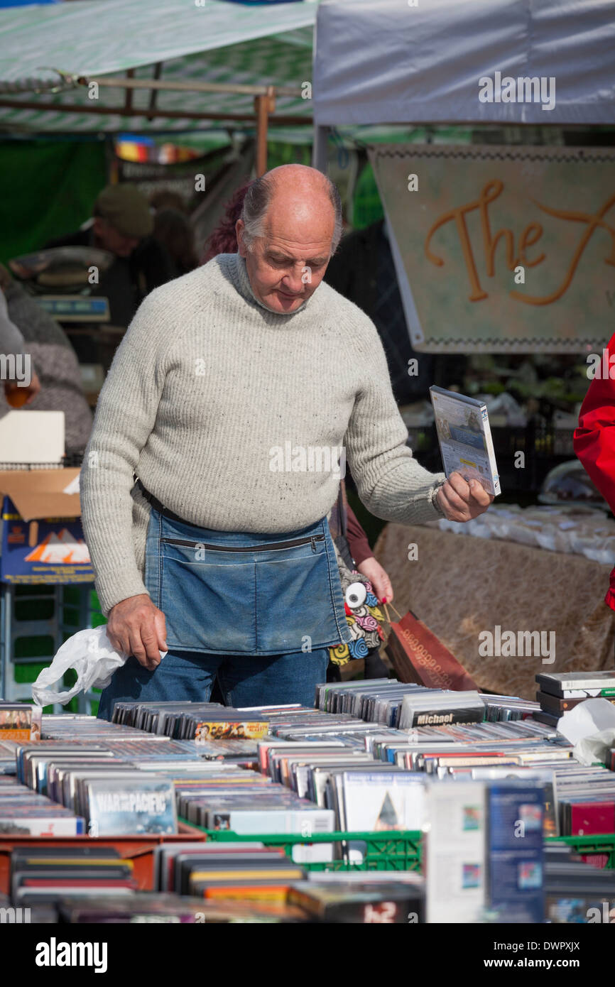 Commerciante di mercato con custodia denaro vendendo i DVD dal mercato in stallo. Foto Stock